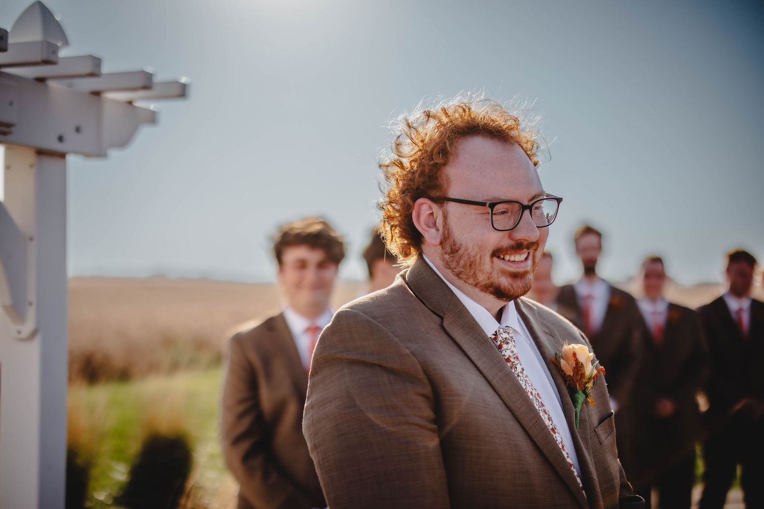 Emotional wedding ceremony moment under white pergola against rural landscape.