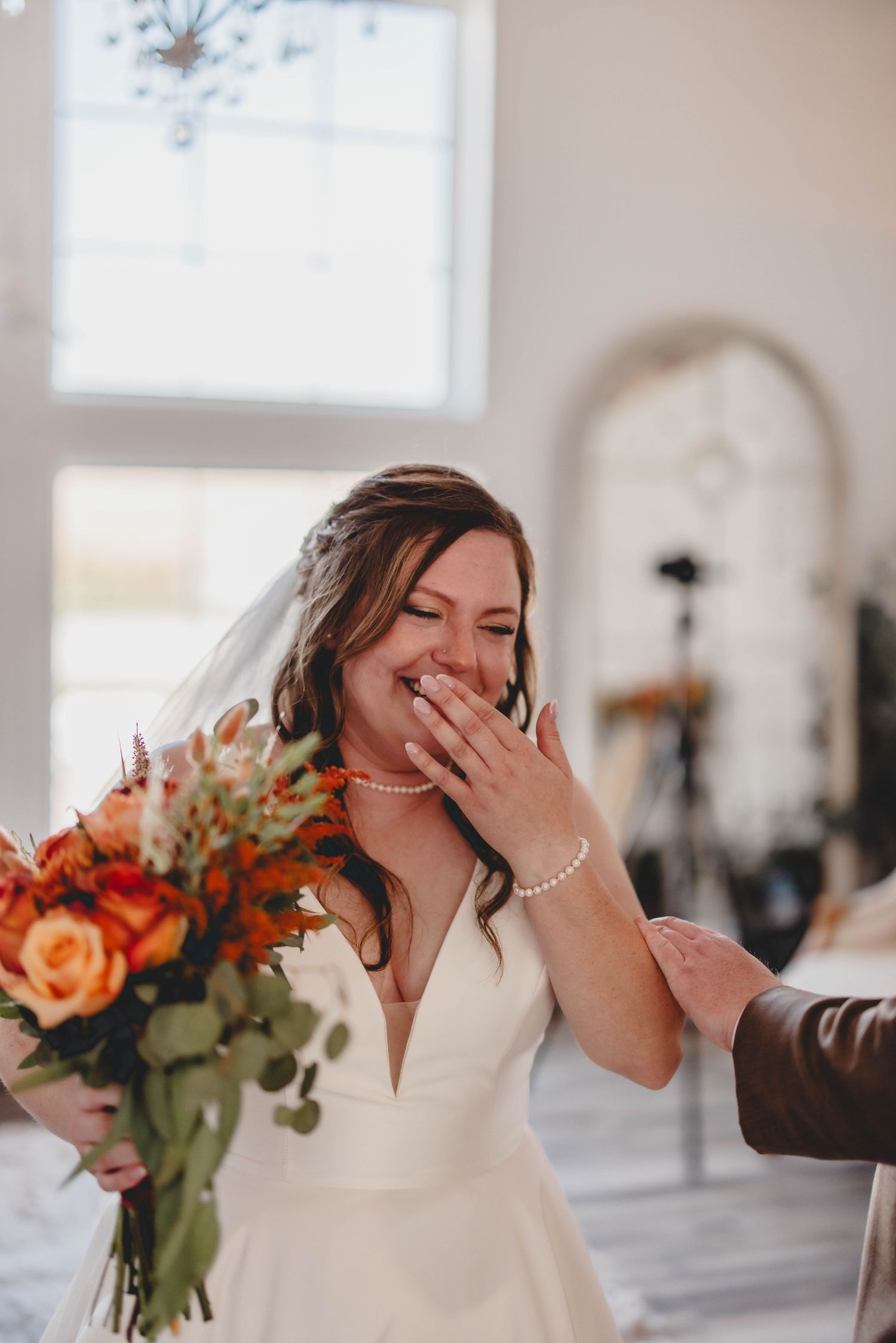 Spontaneous moment of joy captured during wedding with peach roses and greenery bouquet.