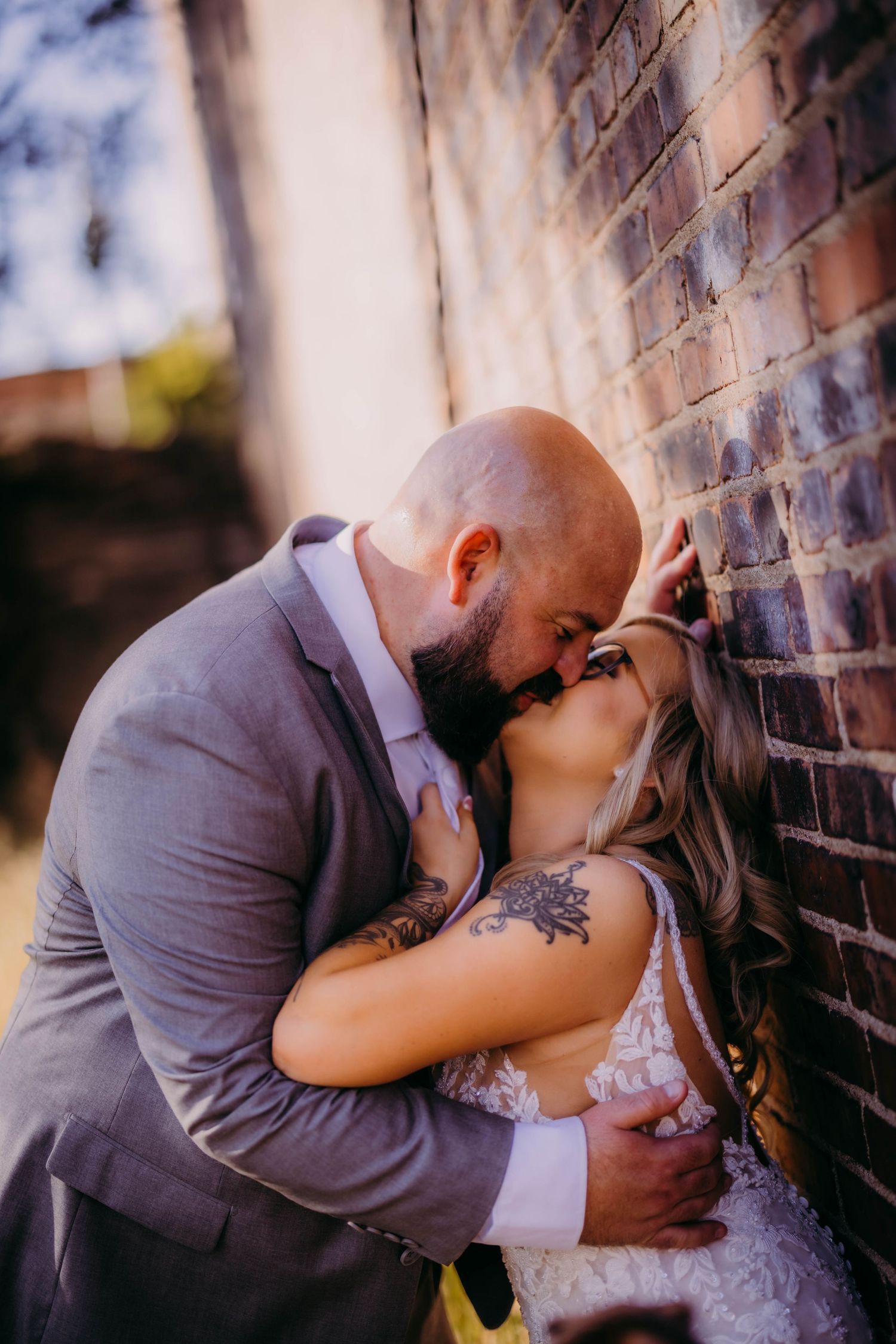 Romantic wedding photo of couple kissing against brick wall.