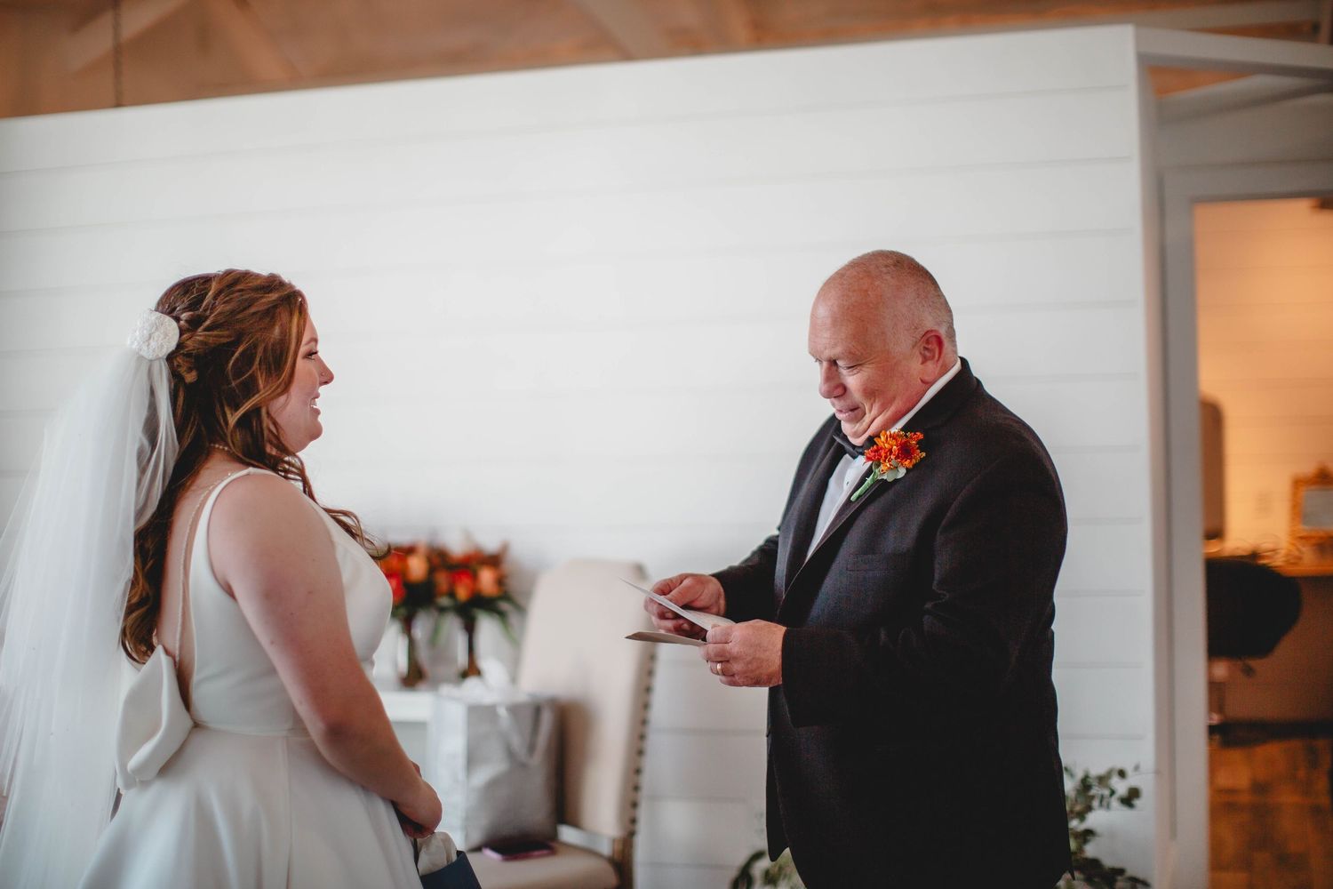 Guest in black suit delivers wedding speech while holding papers.