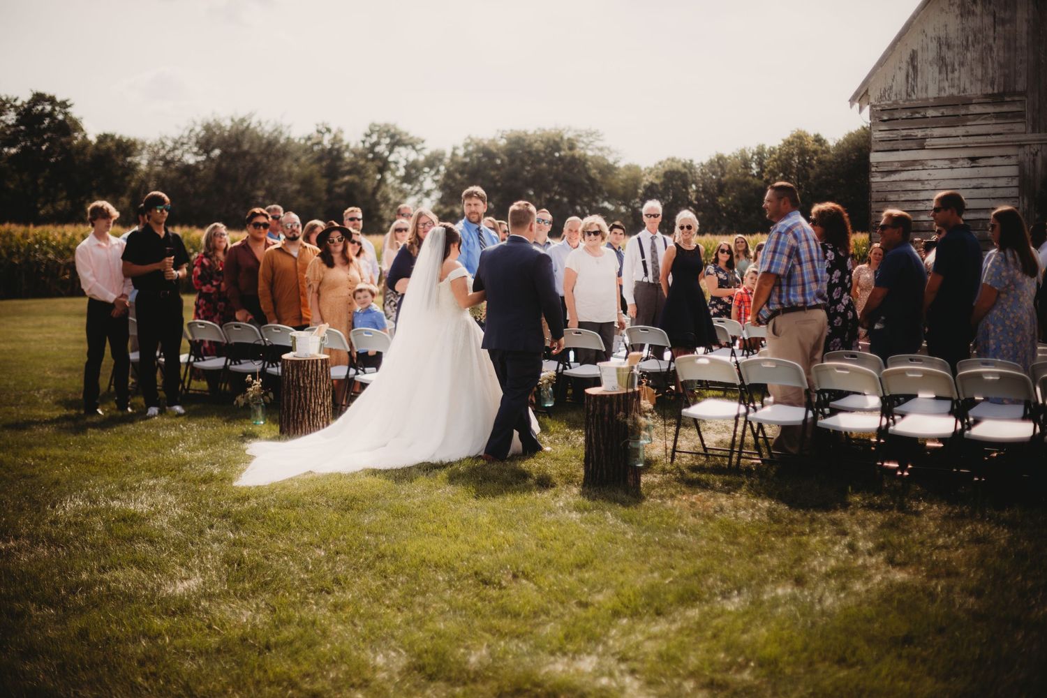 Wedding ceremony recessional with guests standing at rustic farm venue.