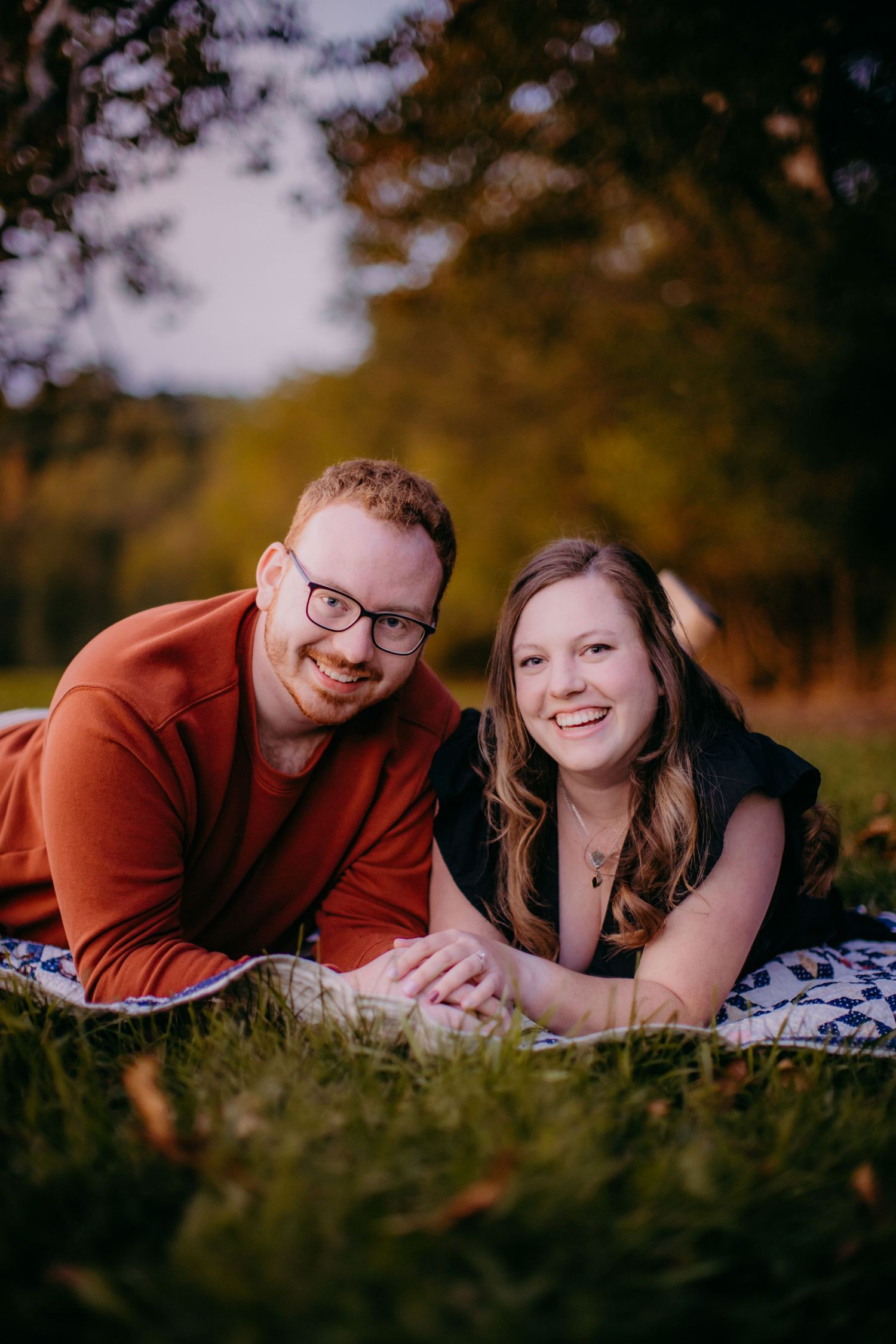 Couple relaxing on pattern blanket during outdoor autumn photoshoot.