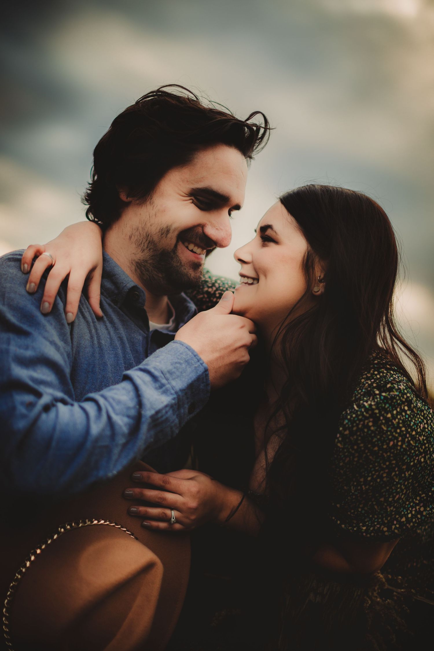 Candid shot of couple laughing and embracing while holding a brown hat.