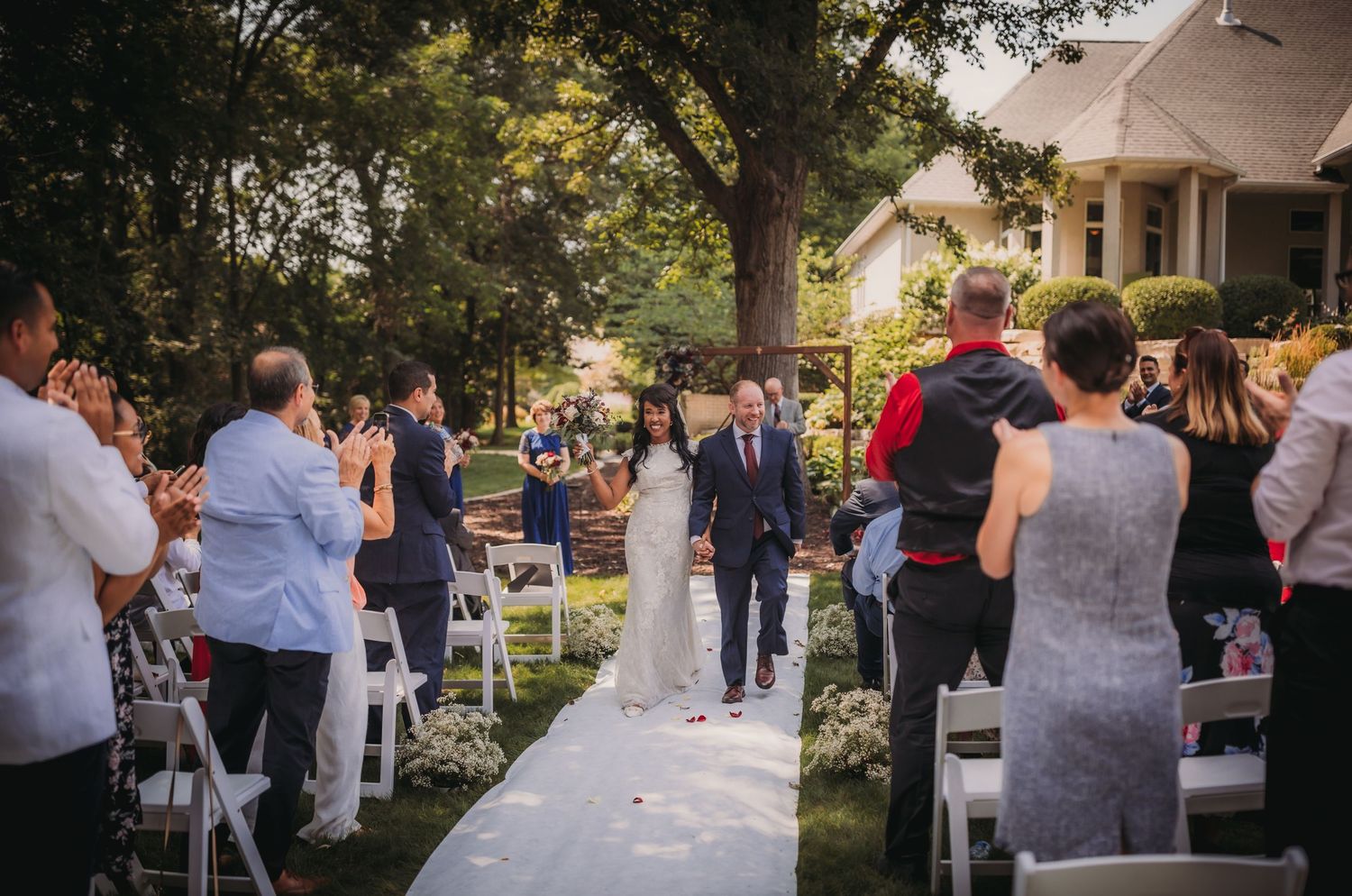 Guests enjoying an outdoor wedding celebration with white chairs and natural scenery.