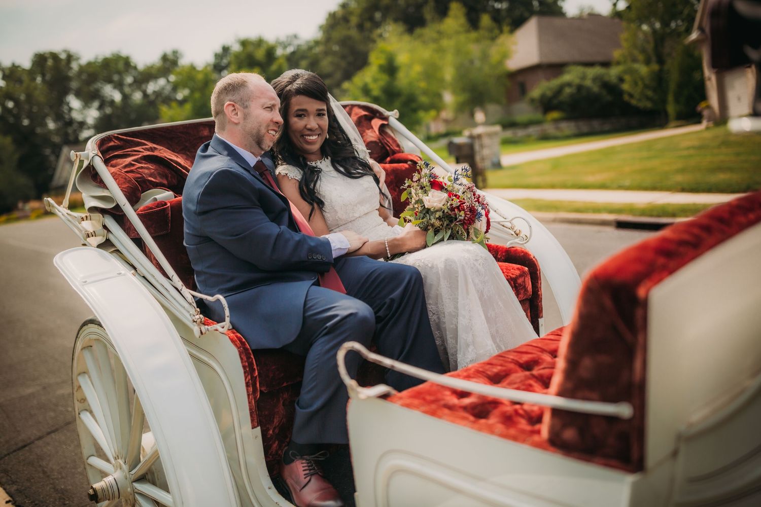 A happy couple enjoys their wedding day ride in a vintage white carriage.