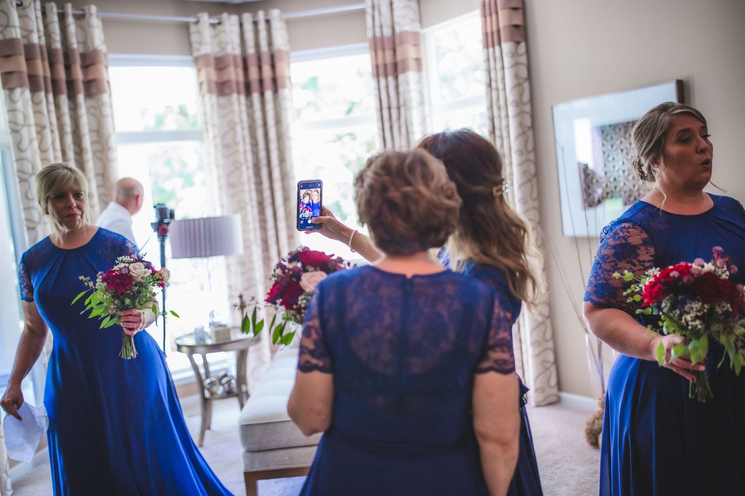 Wedding party members gathered in a bright room wearing coordinated blue and floral outfits.