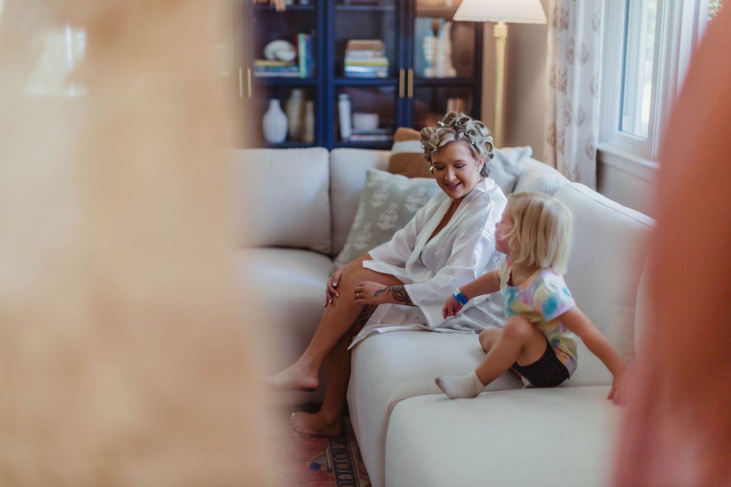 Wedding morning preparations on a cozy white couch in a sunlit living room.