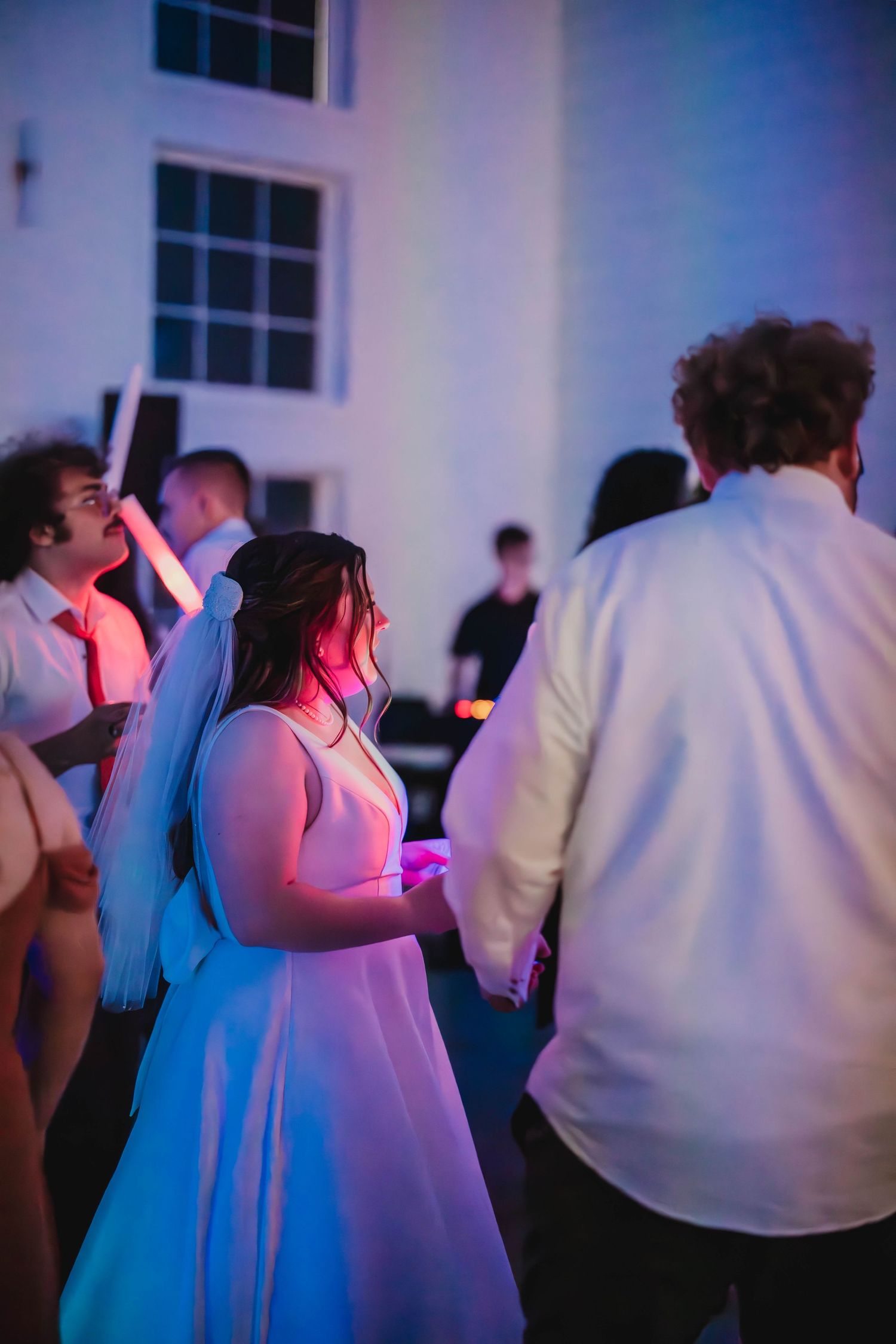 Wedding reception dance floor illuminated with colorful lights as guests celebrate.