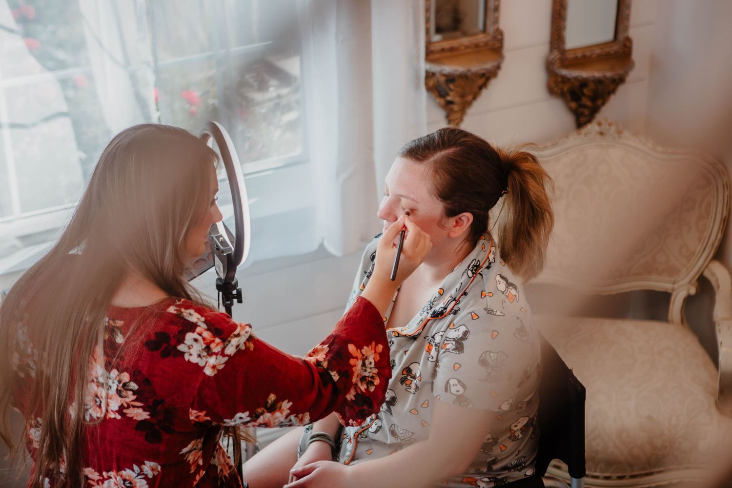 Makeup artist applying cosmetics in a bright, elegant dressing room.