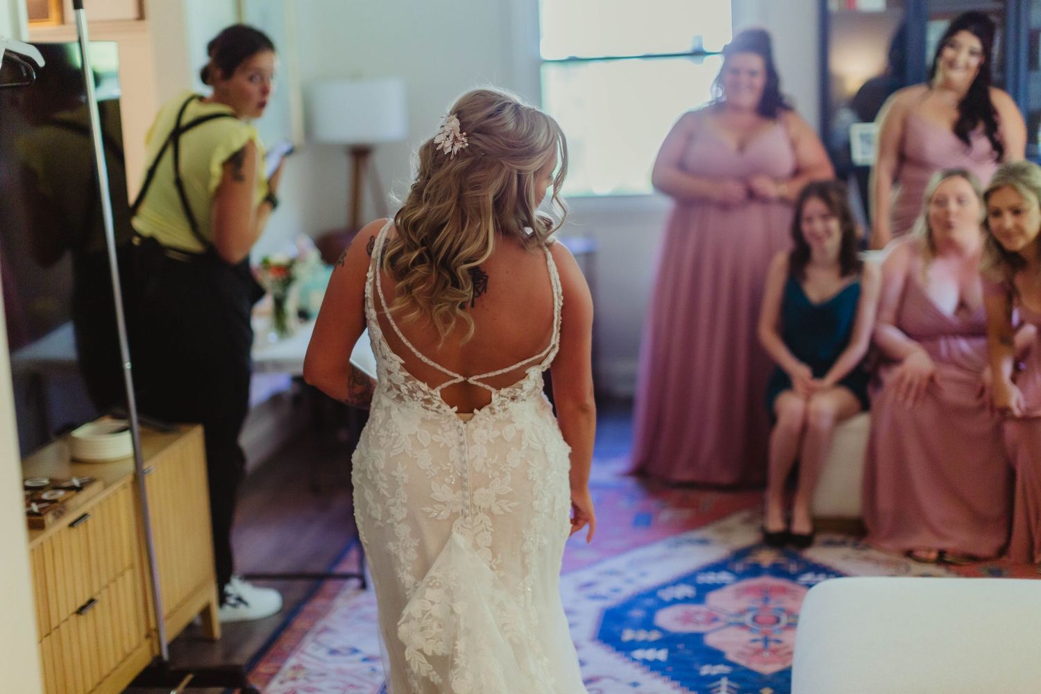 Wedding party members gather in a modern room decorated with pink and white accents.