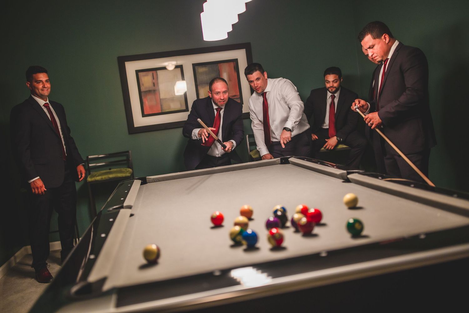 Group watching intently as billiard balls scatter across the pool table during a formal event.
