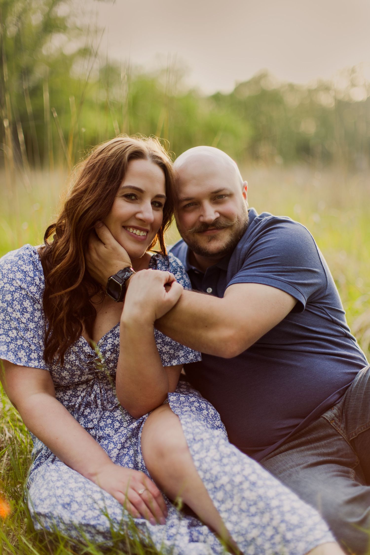 Candid moment between couple laughing and embracing in golden sunlit field.