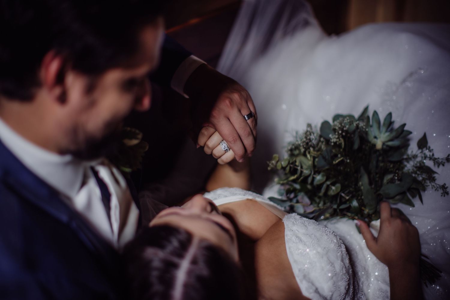 A romantic wedding moment with a couple embracing while holding a green bouquet.