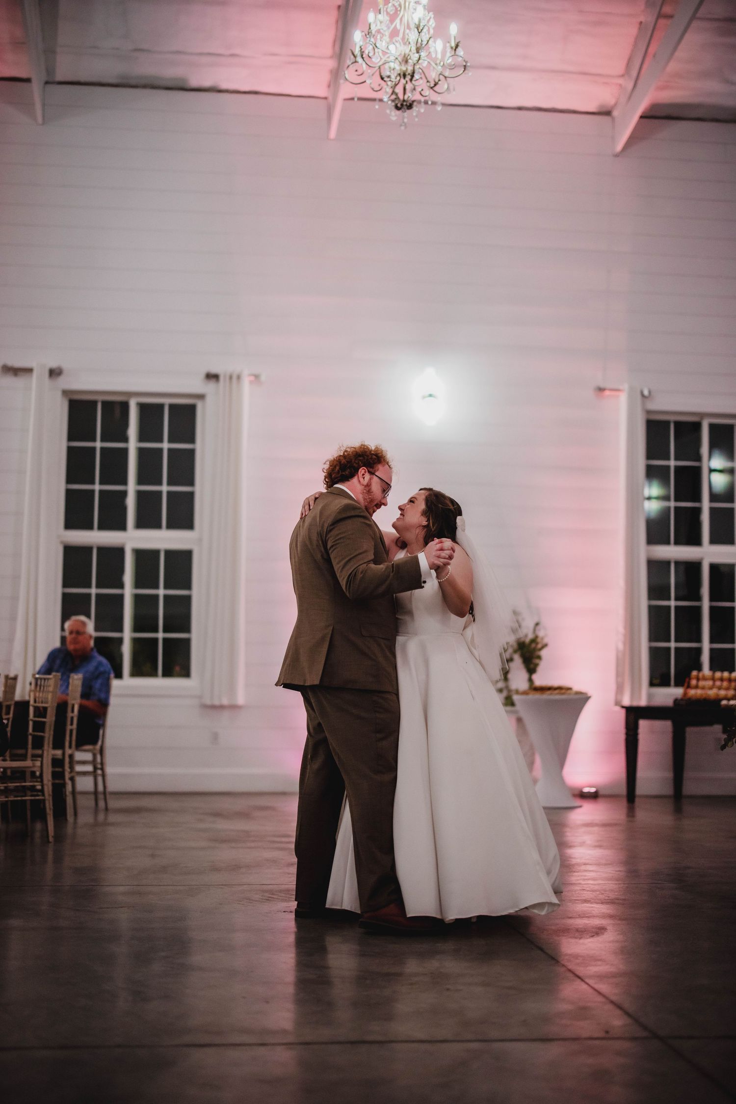 A romantic dance moment between newlyweds in a beautifully lit reception venue with chandelier.