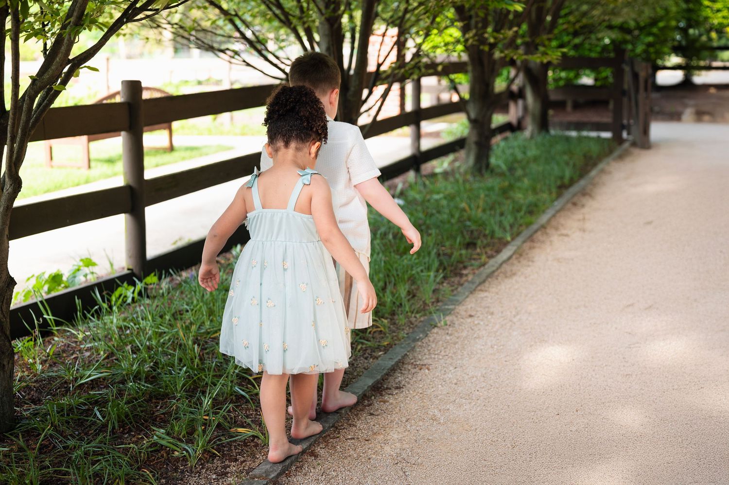 Barefoot siblings balancing along a path at Franklin Park during a playful child-led photo session