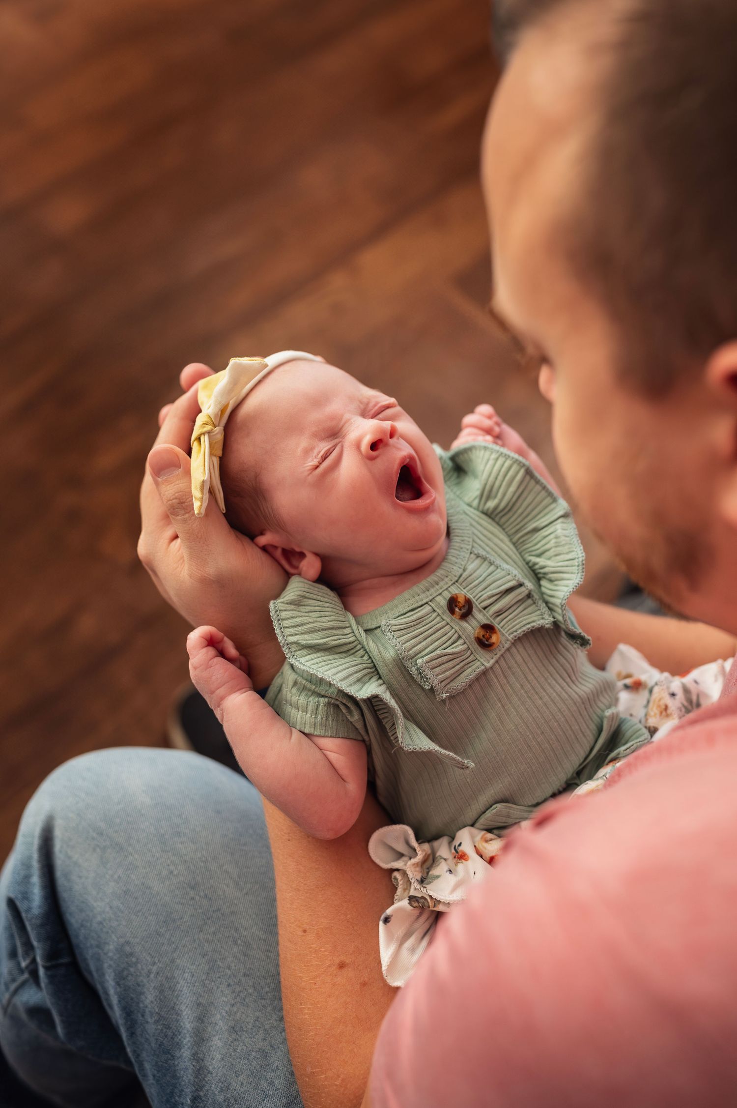 Newborn yawns in dad’s arms during cozy in-home session—Westerville newborn photographer