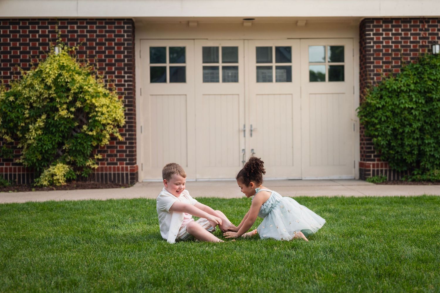Siblings playing on the grass and laughing during a joyful family photo session in Columbus