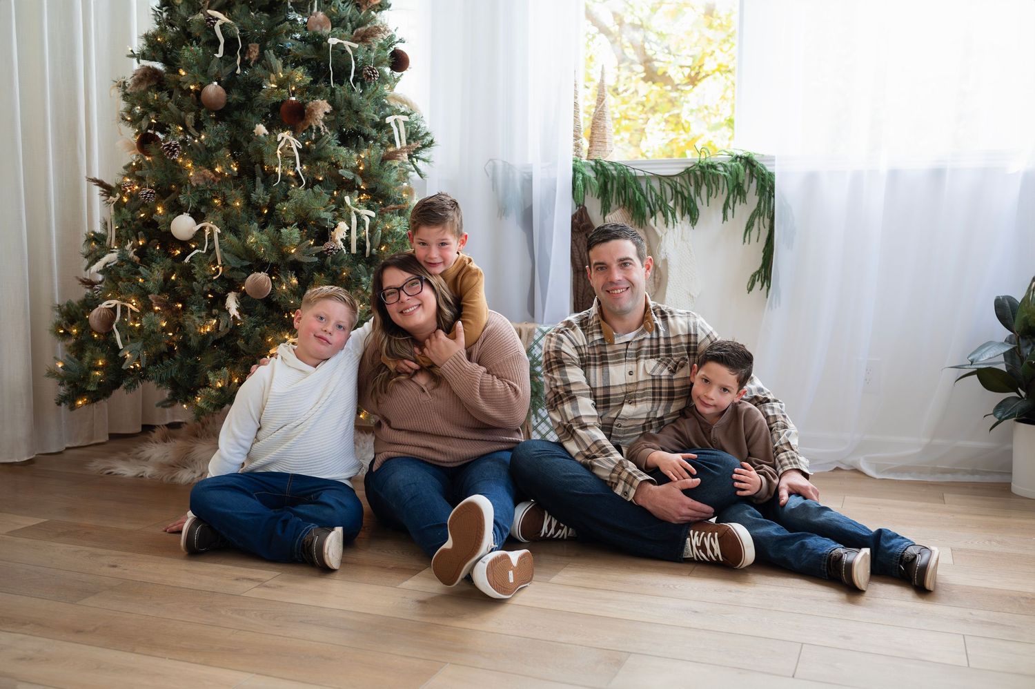 Family of five sitting together in a cozy indoor Christmas setup during a Boundless Joy holiday mini session in Columbus