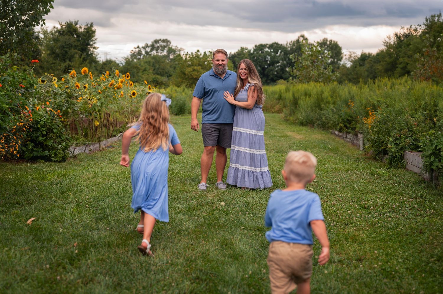 Kids run to parents during a playful summer mini session in a sunflower field near Columbus, Ohio