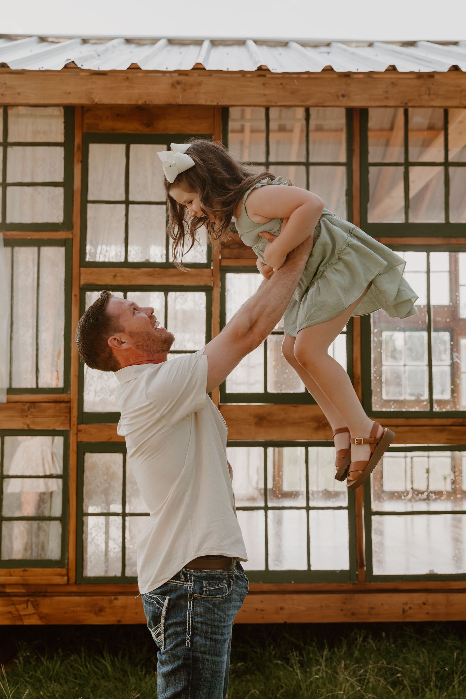 Two people share intimate dance poses in front of rustic wooden windows in a romantic lifestyle photoshoot.