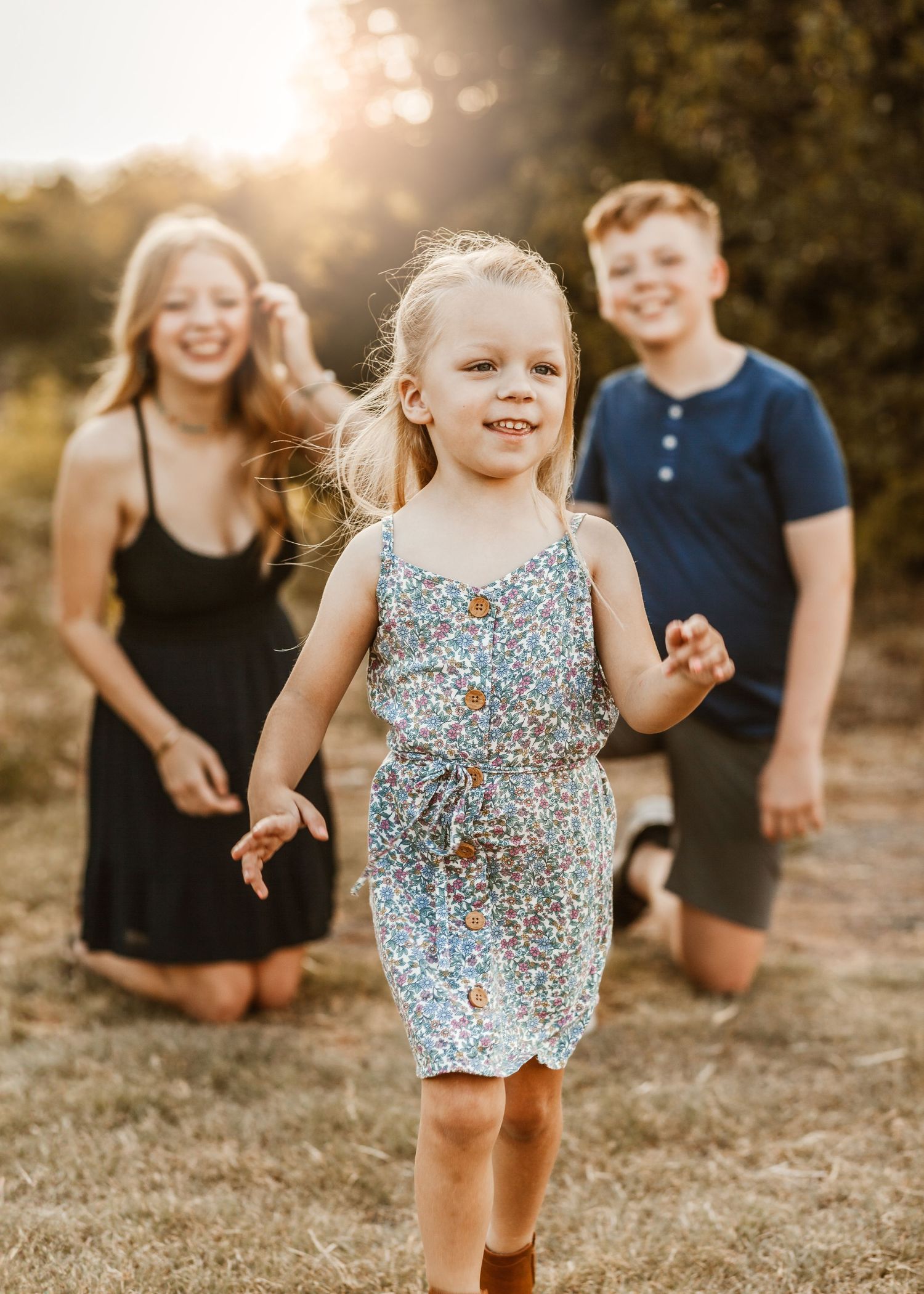 Family laughing and playing together outdoors during golden hour sunset in a casual candid moment.