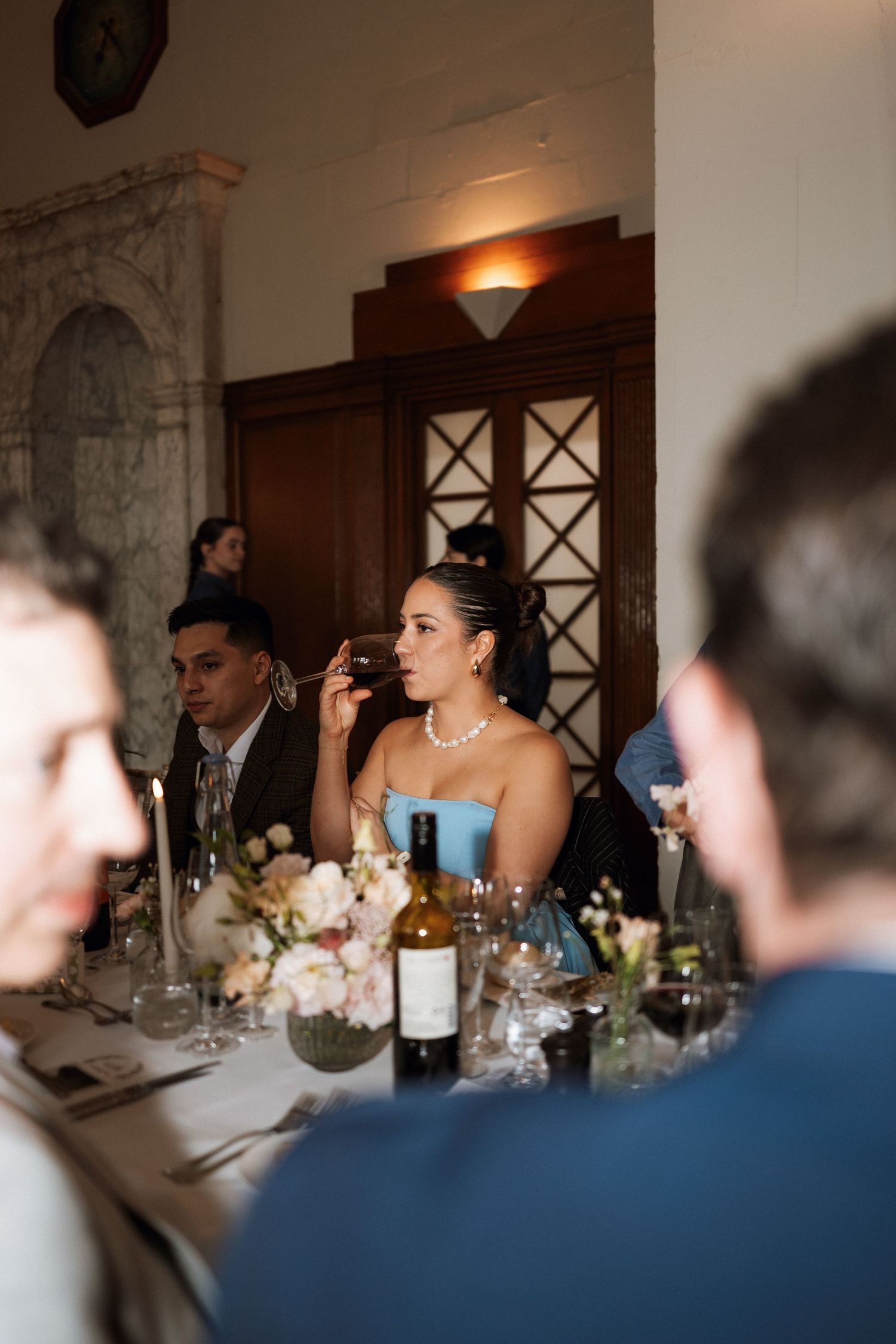 Elegant wedding reception dinner party table with fine wine and floral centerpieces at an ornate venue with stone archways.