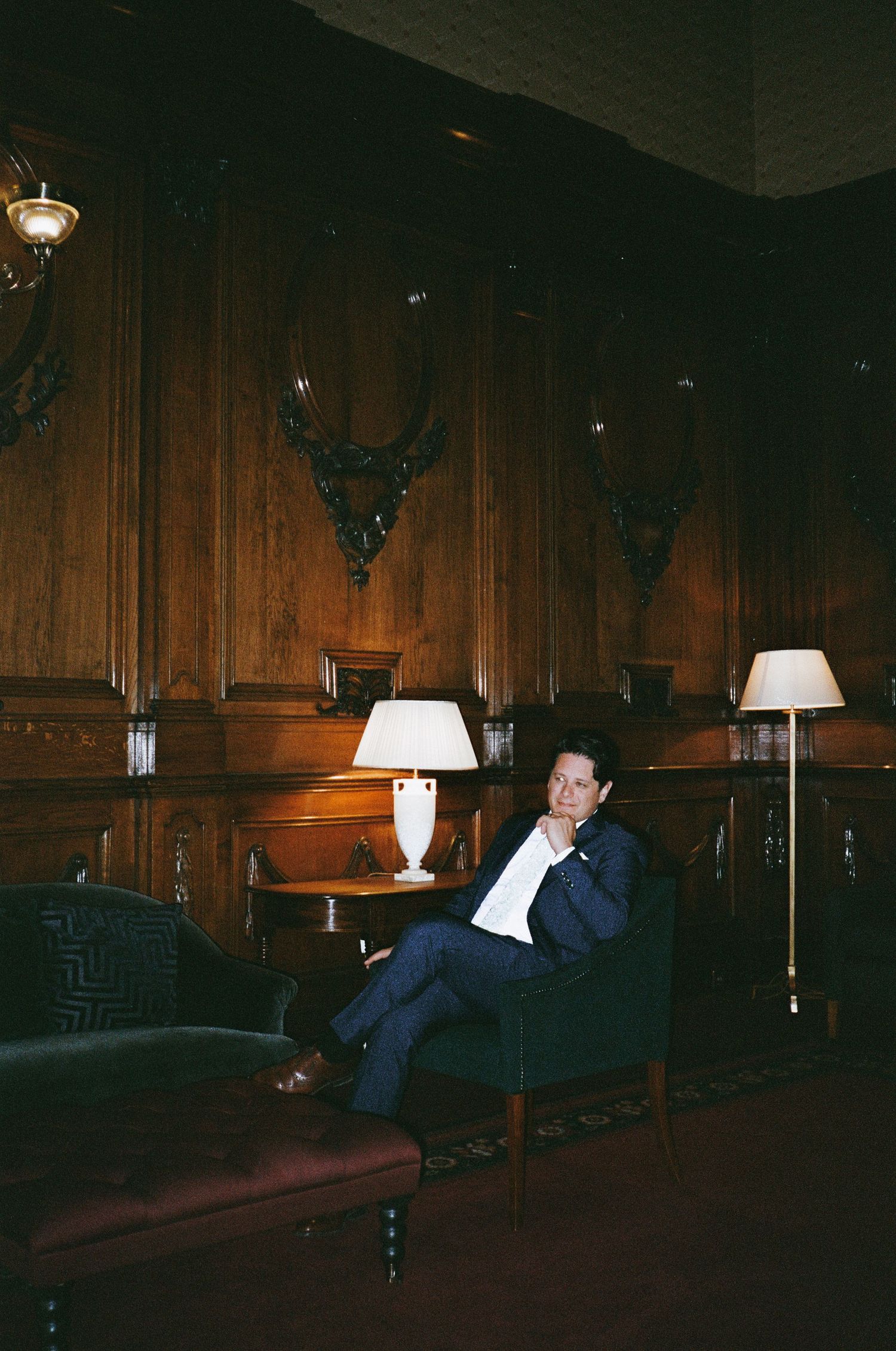 A dimly lit room with wood-paneled walls features elegant table lamps and mounted deer heads as decor.