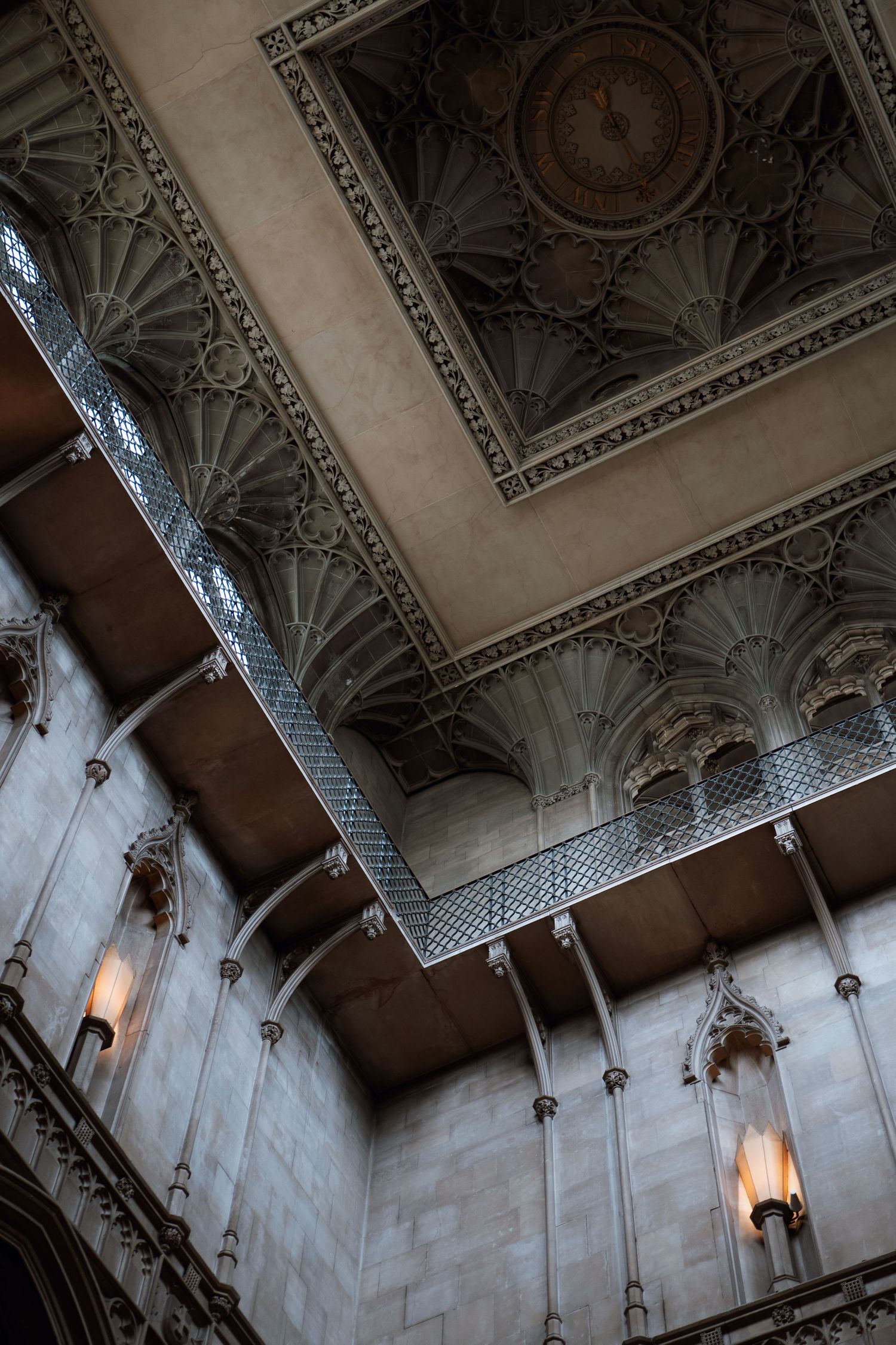 Ornate architectural details of a classical ceiling with decorative moldings, wall sconces and fan vaulting in a historic building.