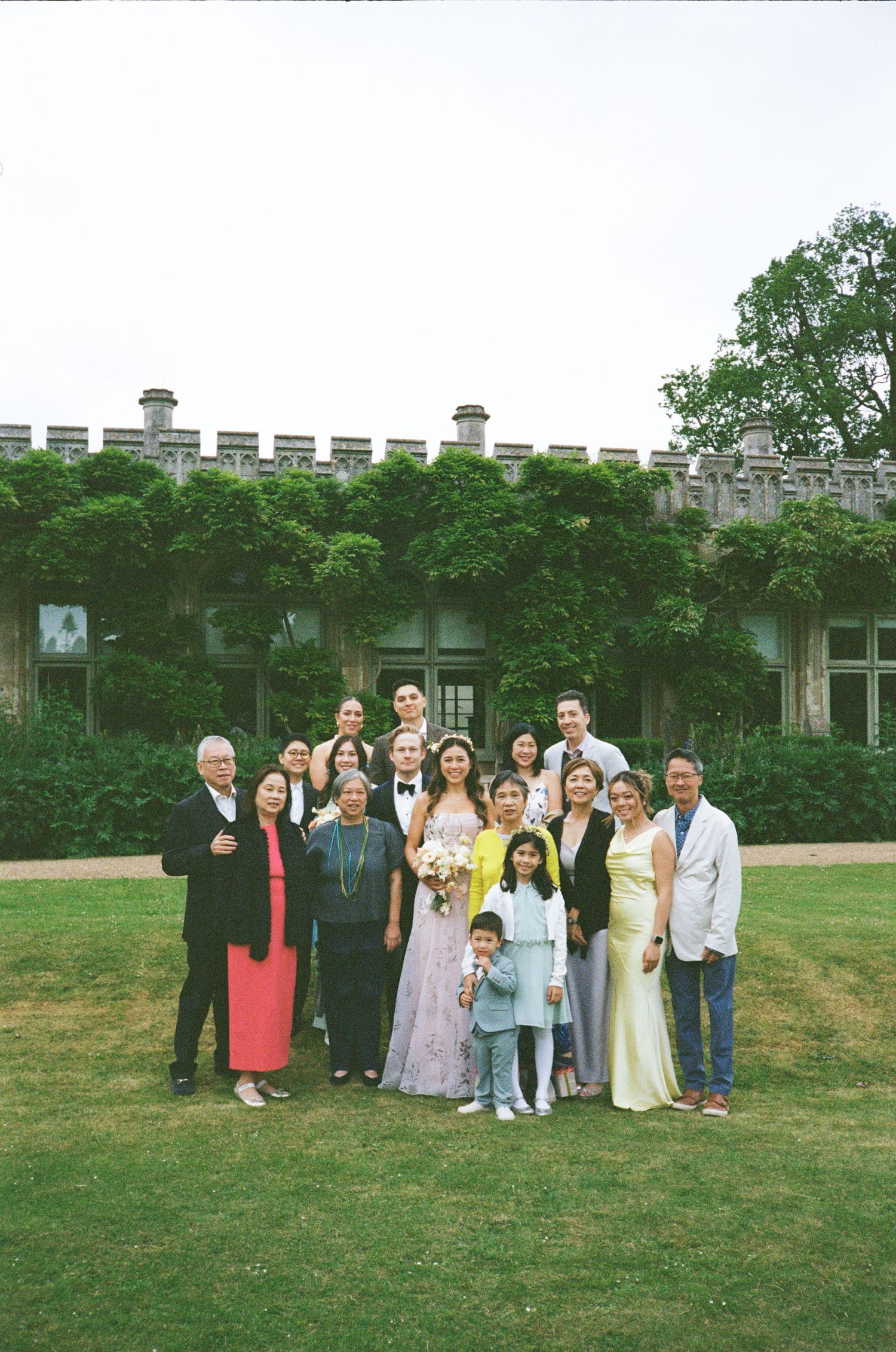 Group photo taken on a lawn in front of an ivy-covered stone building with crenellated walls.