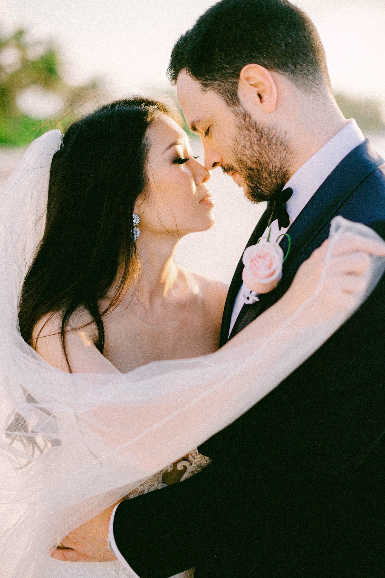A romantic wedding moment captured in soft sunlight as newlyweds share an intimate embrace.