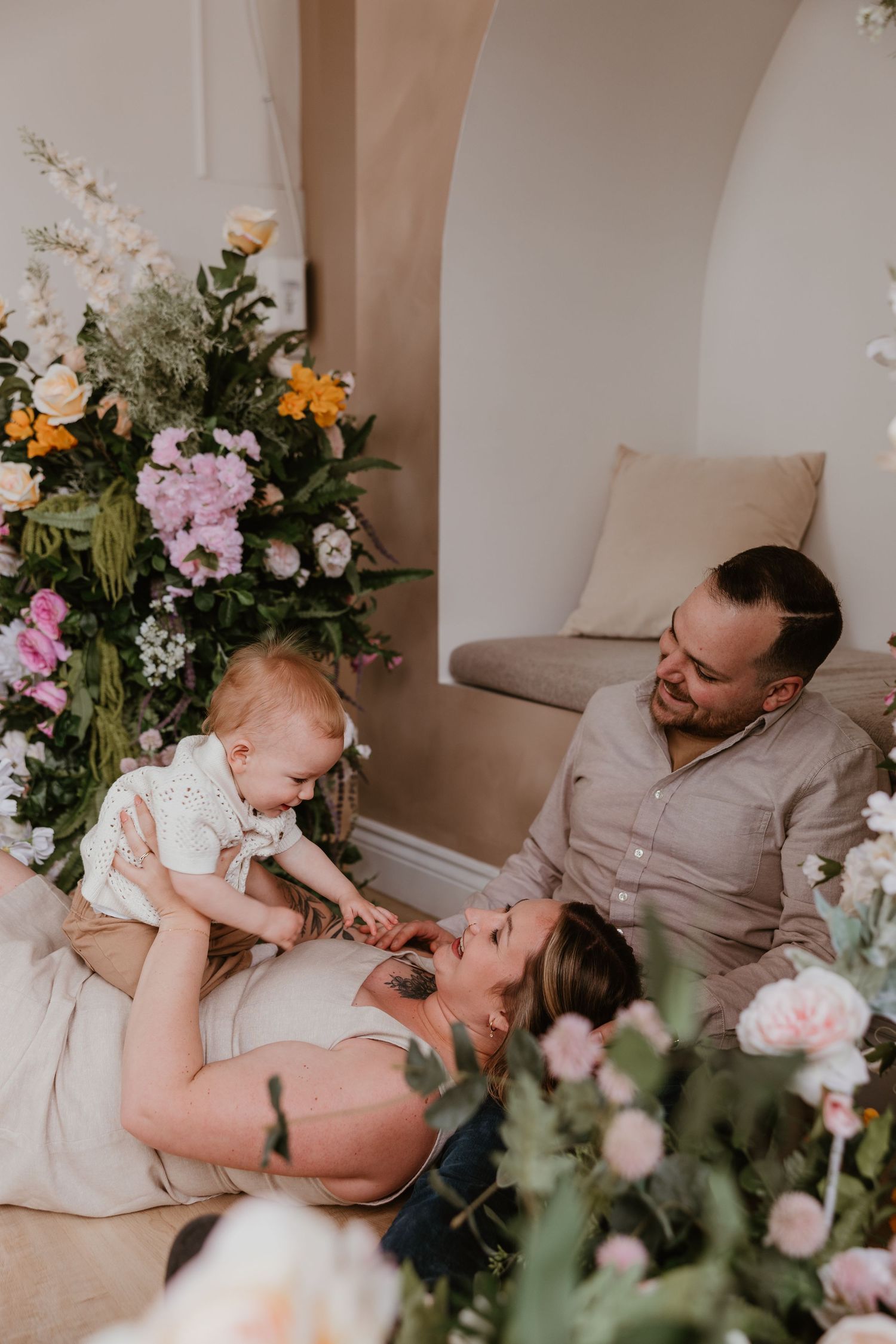 Family photo session with floral decorations and soft lighting in an intimate indoor setting.