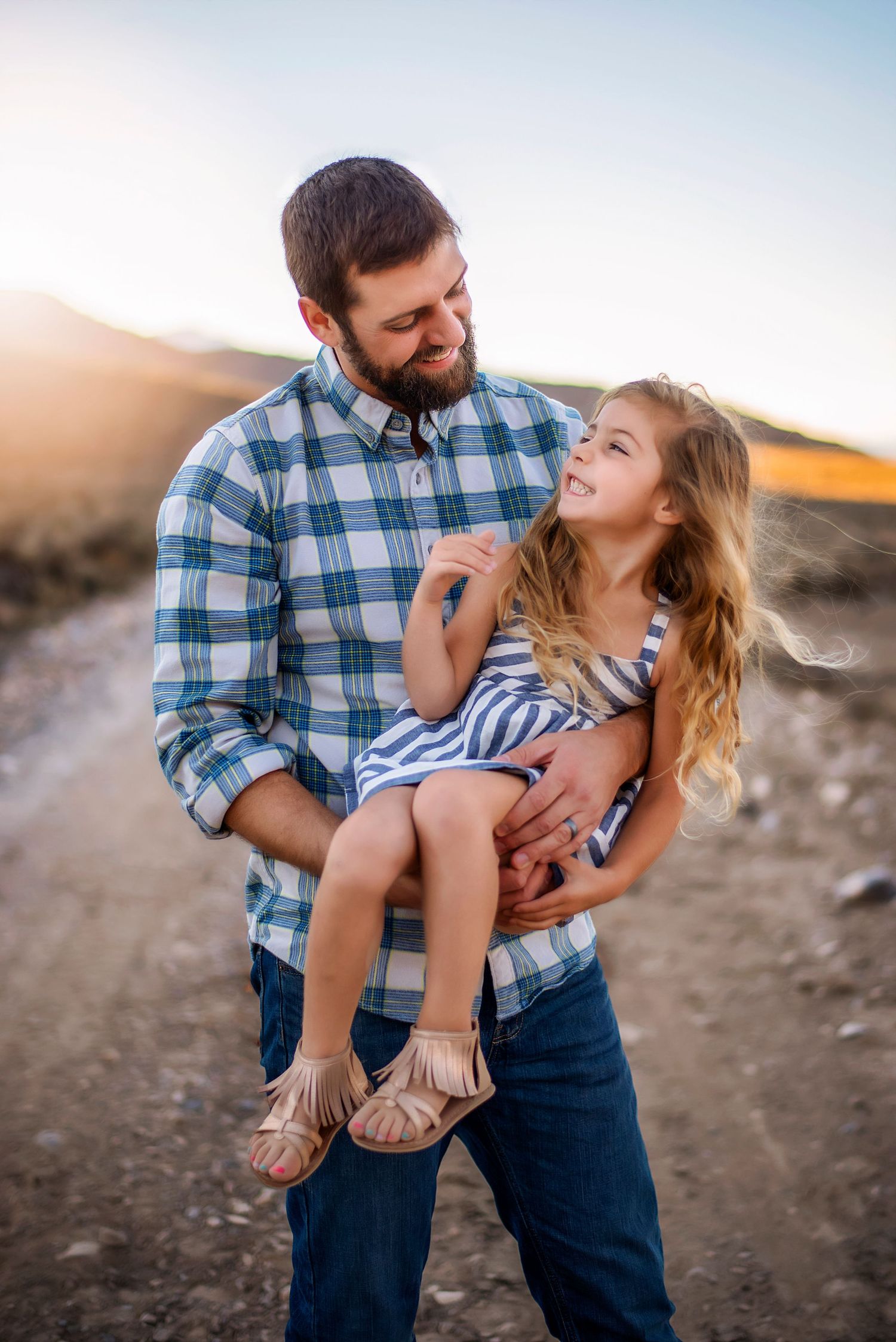 Dad holds his daughter as they look at each other during a family photoshoot in the desert near Wenatchee, Washington.