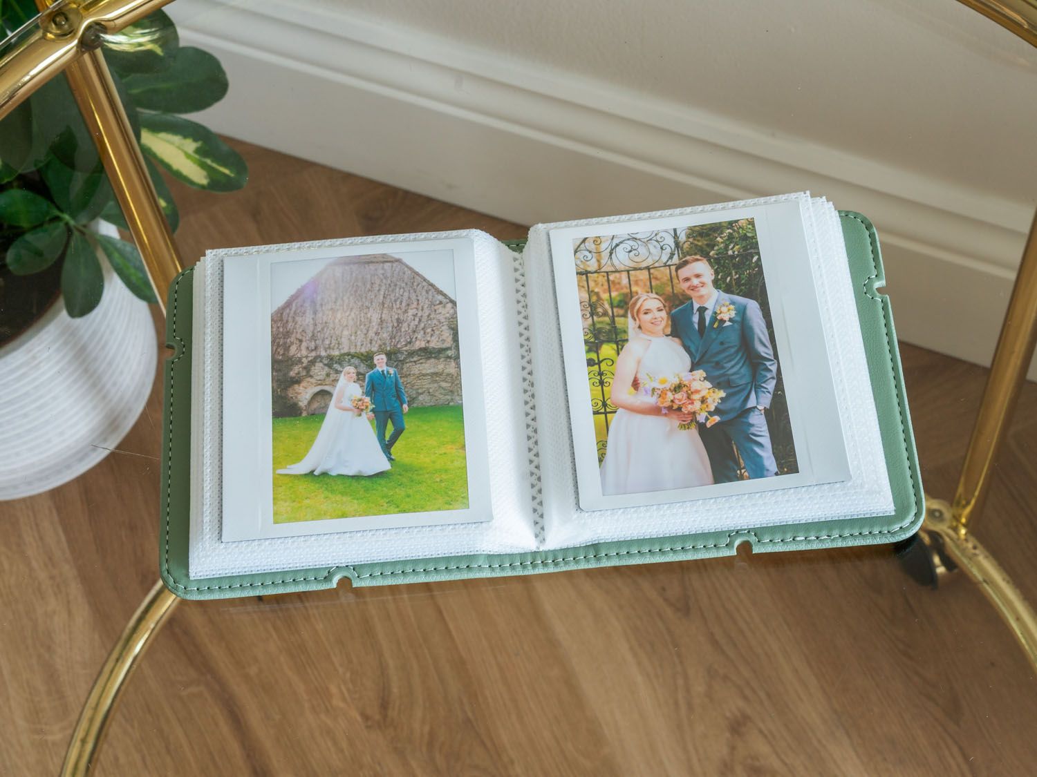 Open wedding album showing outdoor ceremony photographs with mint green binding.
