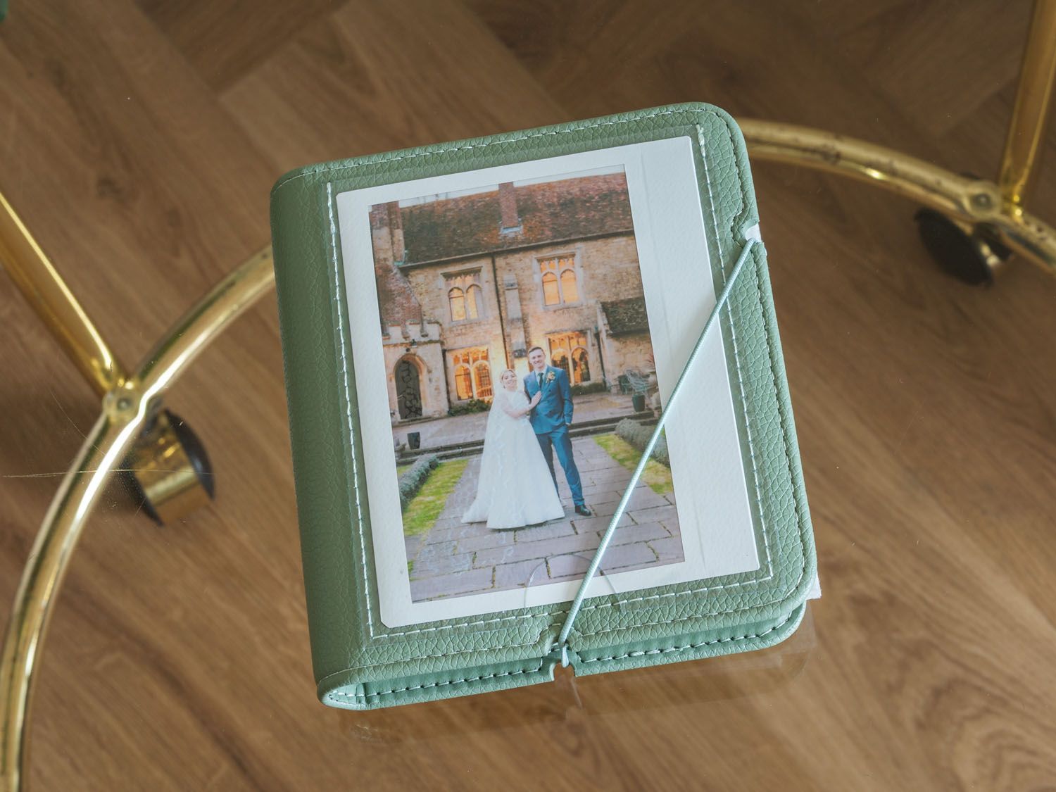 Mint green leather photo album with wedding photograph and decorative ribbon closure.