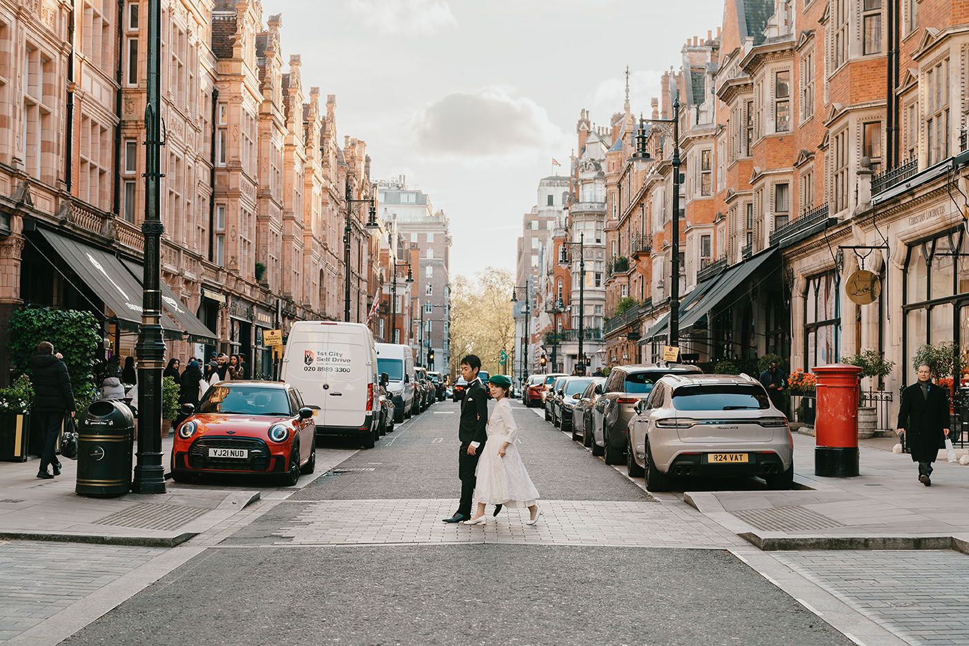 A person walking their dog down a classic London street lined with Victorian brick buildings.
