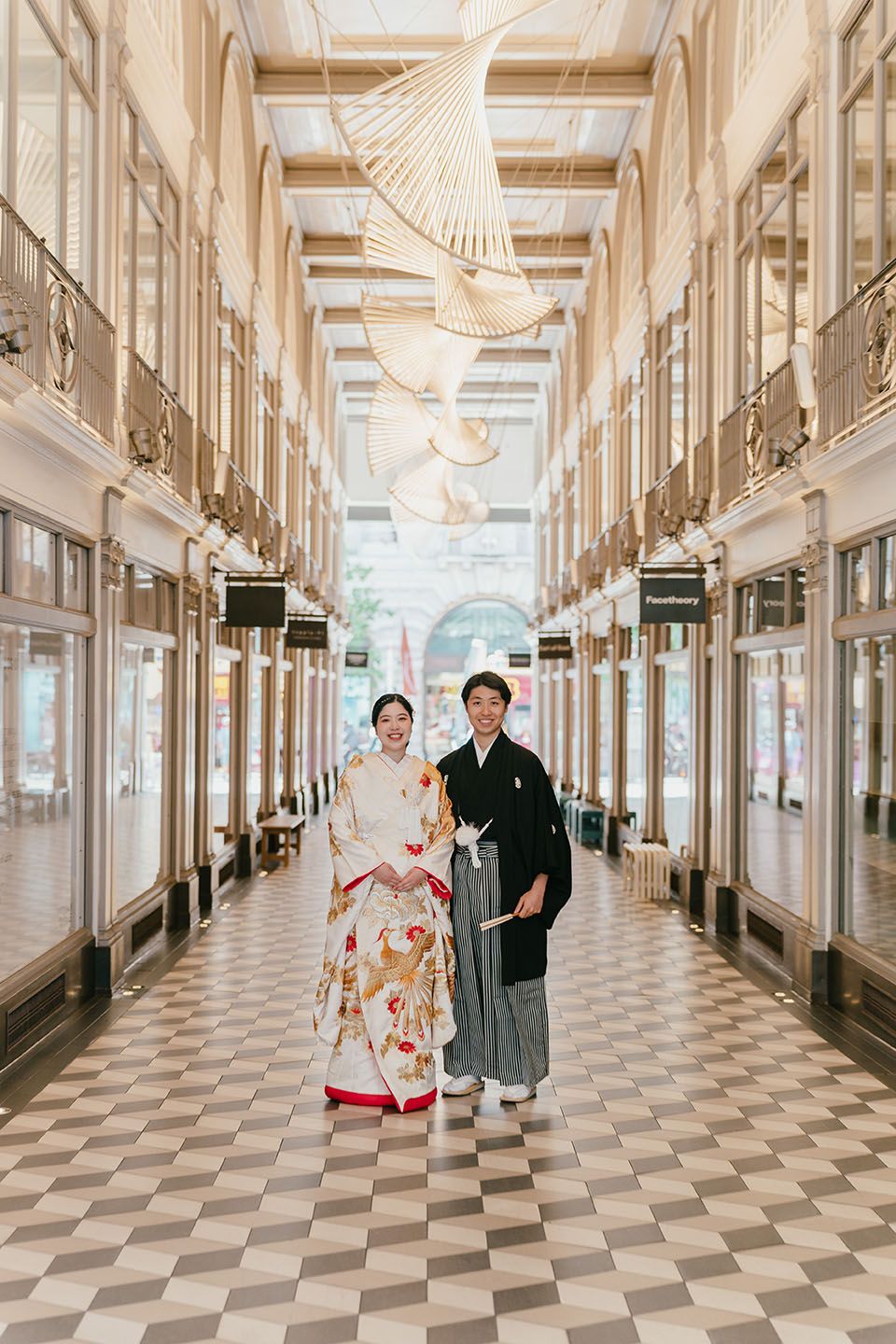 Elegant gallery hallway with checkered floors and ornate white columns features traditional Japanese wedding attire.