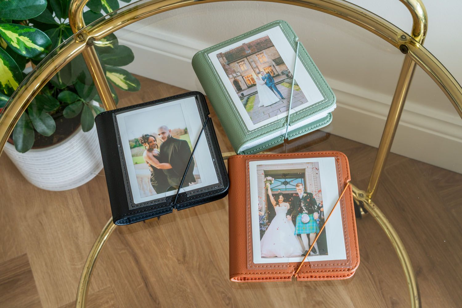 Collection of wedding photo albums in different colors displayed on gold metal table.