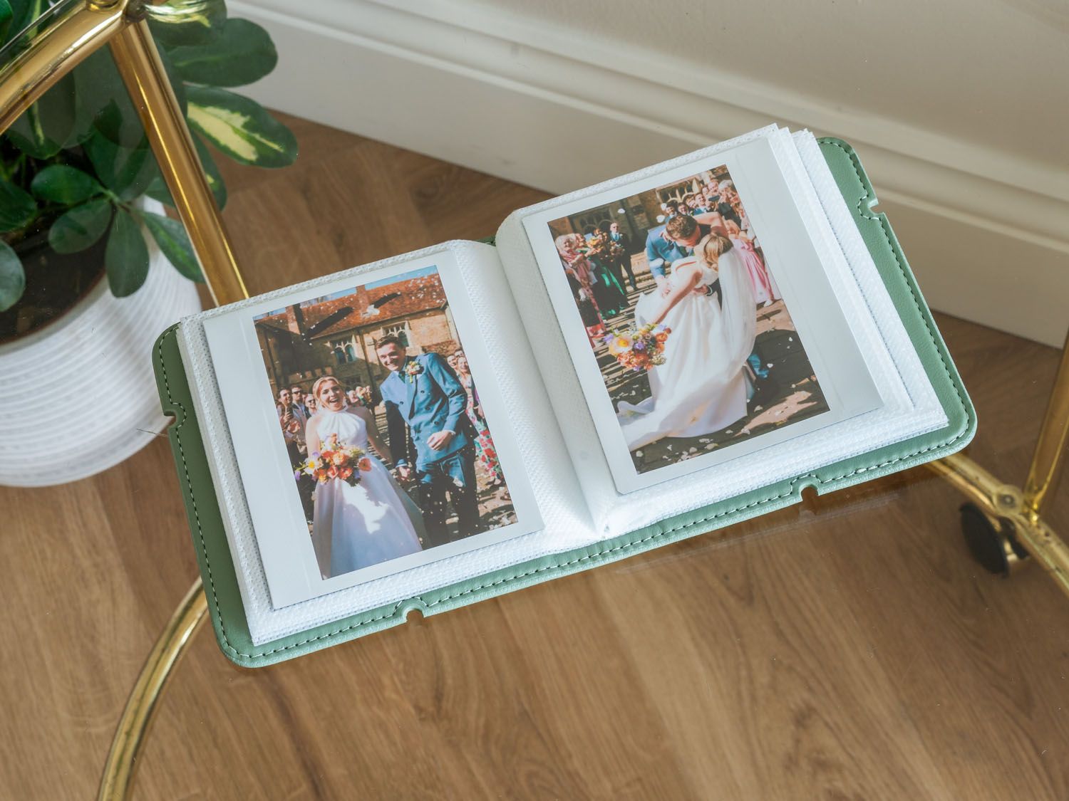 Mint green wedding photo album displaying formal celebration images on wooden floor.