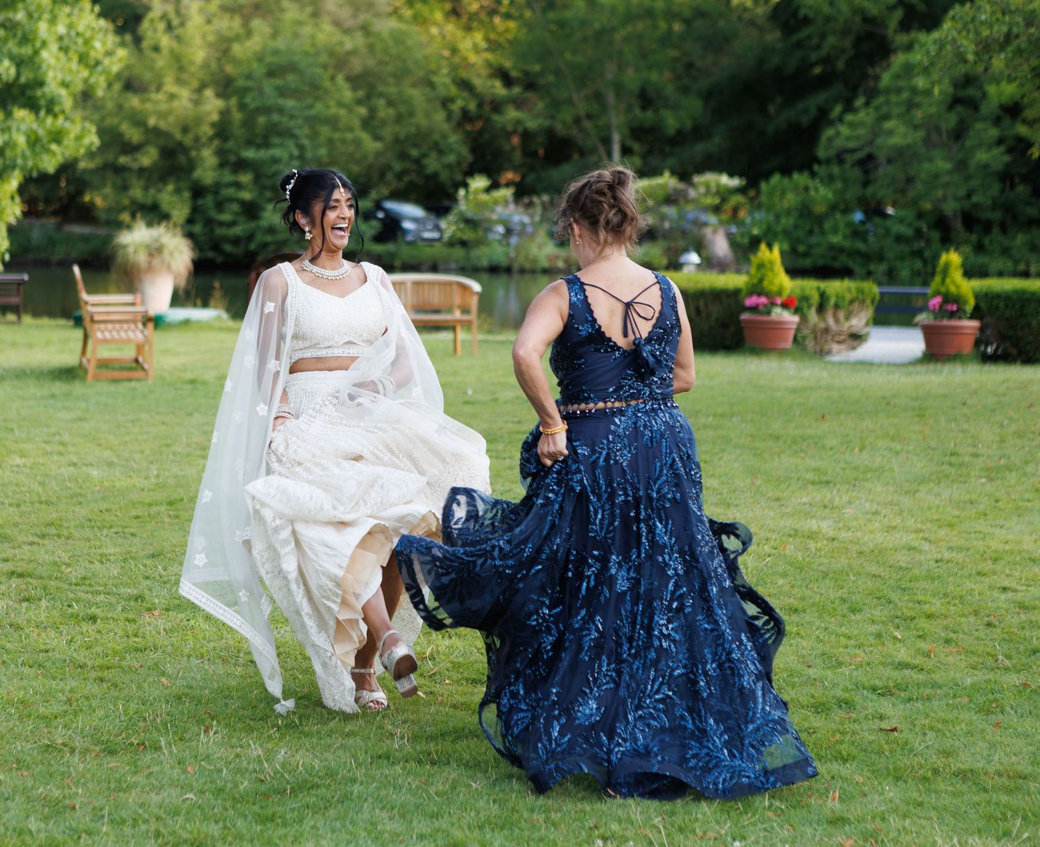 Two people in formal dresses lounging on a grassy lawn during an outdoor event.