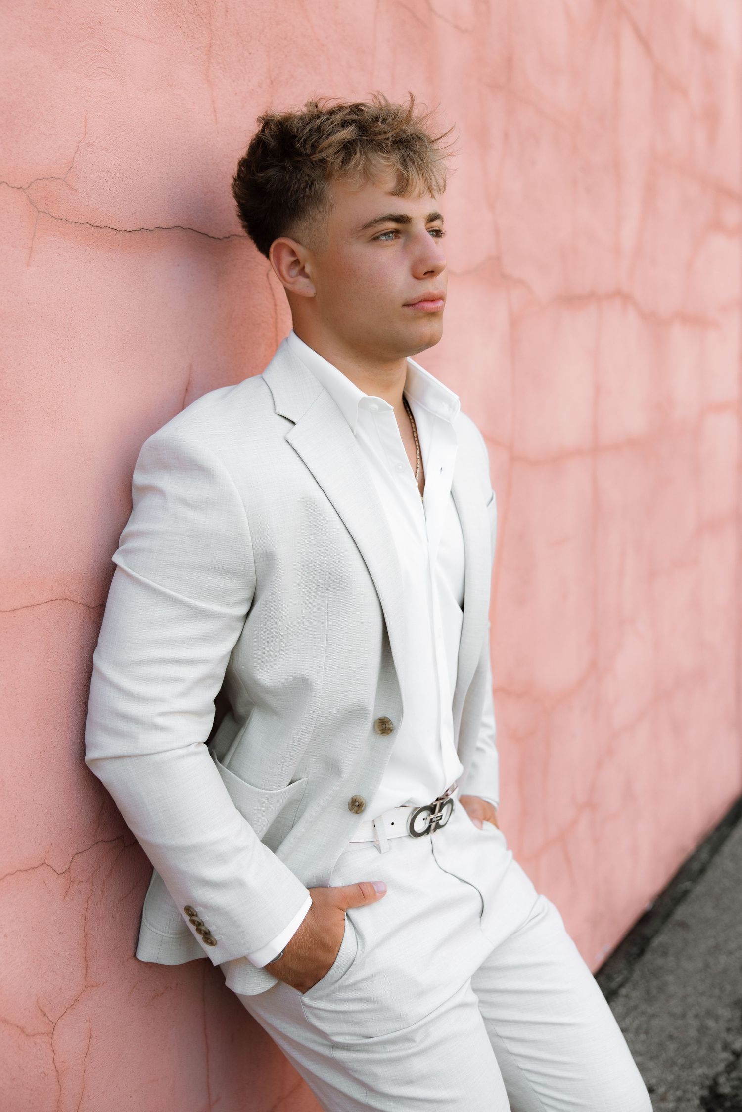A fashion photo series featuring a white suit against a pink textured wall.