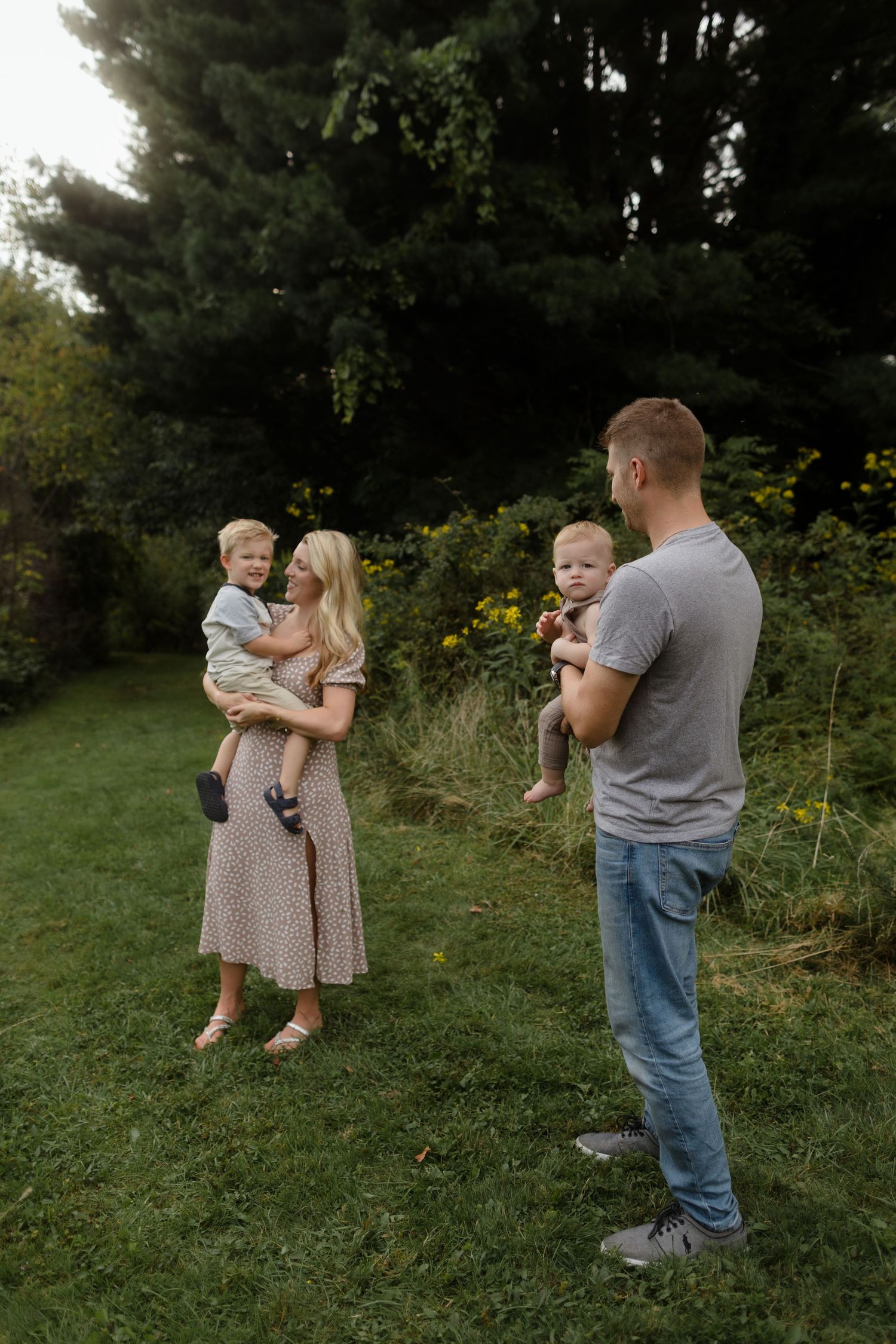 Family enjoying a peaceful moment together in a garden with tall trees and greenery in the background.