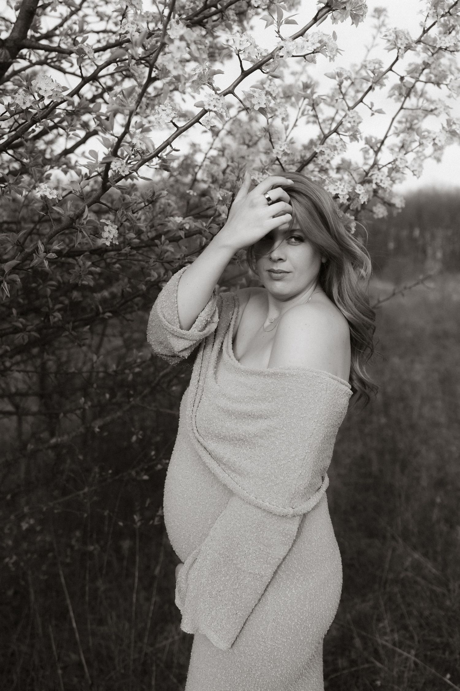Maternity portrait under blooming spring trees in black and white.
