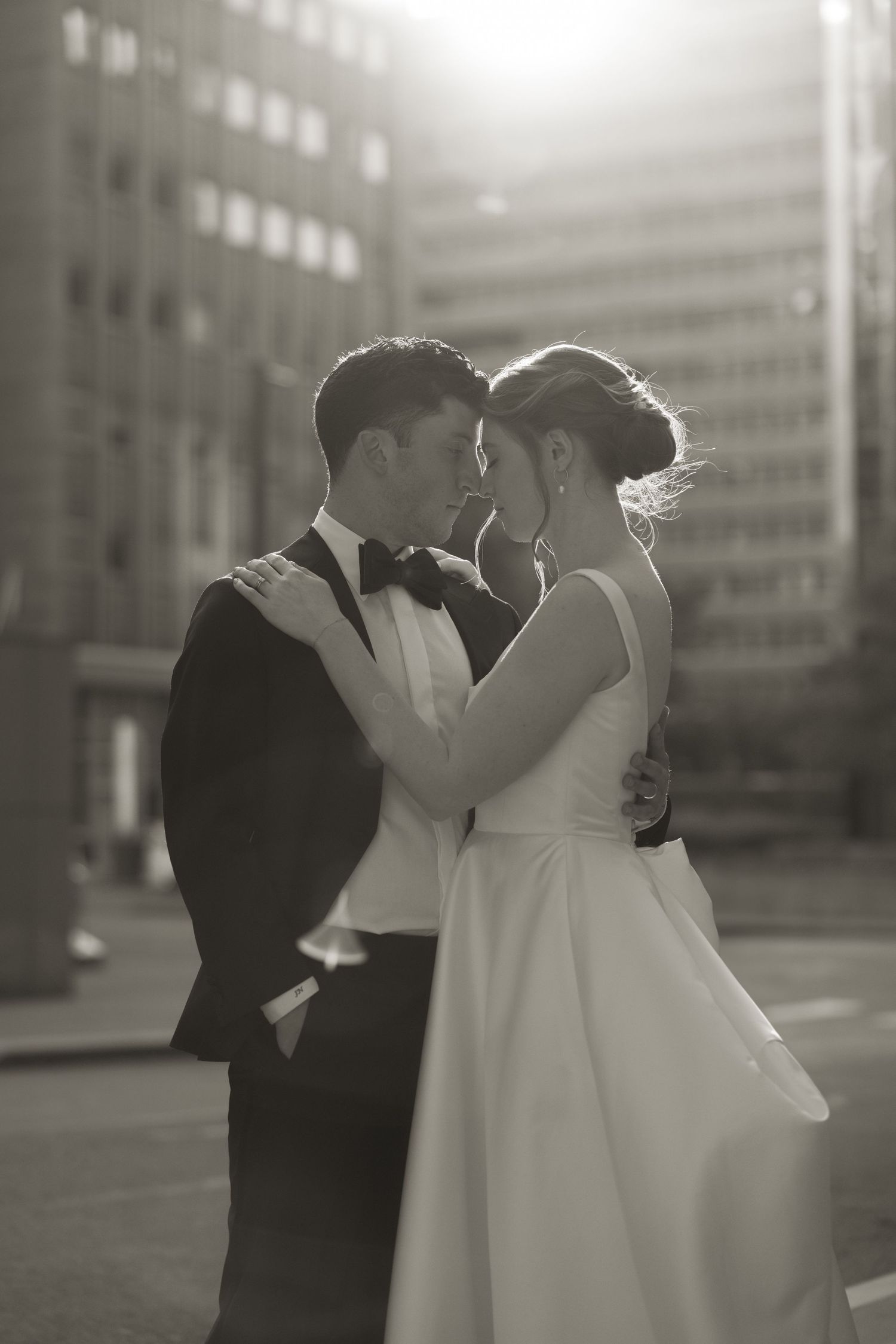 Intimate black and white portrait of couple embracing in urban setting.