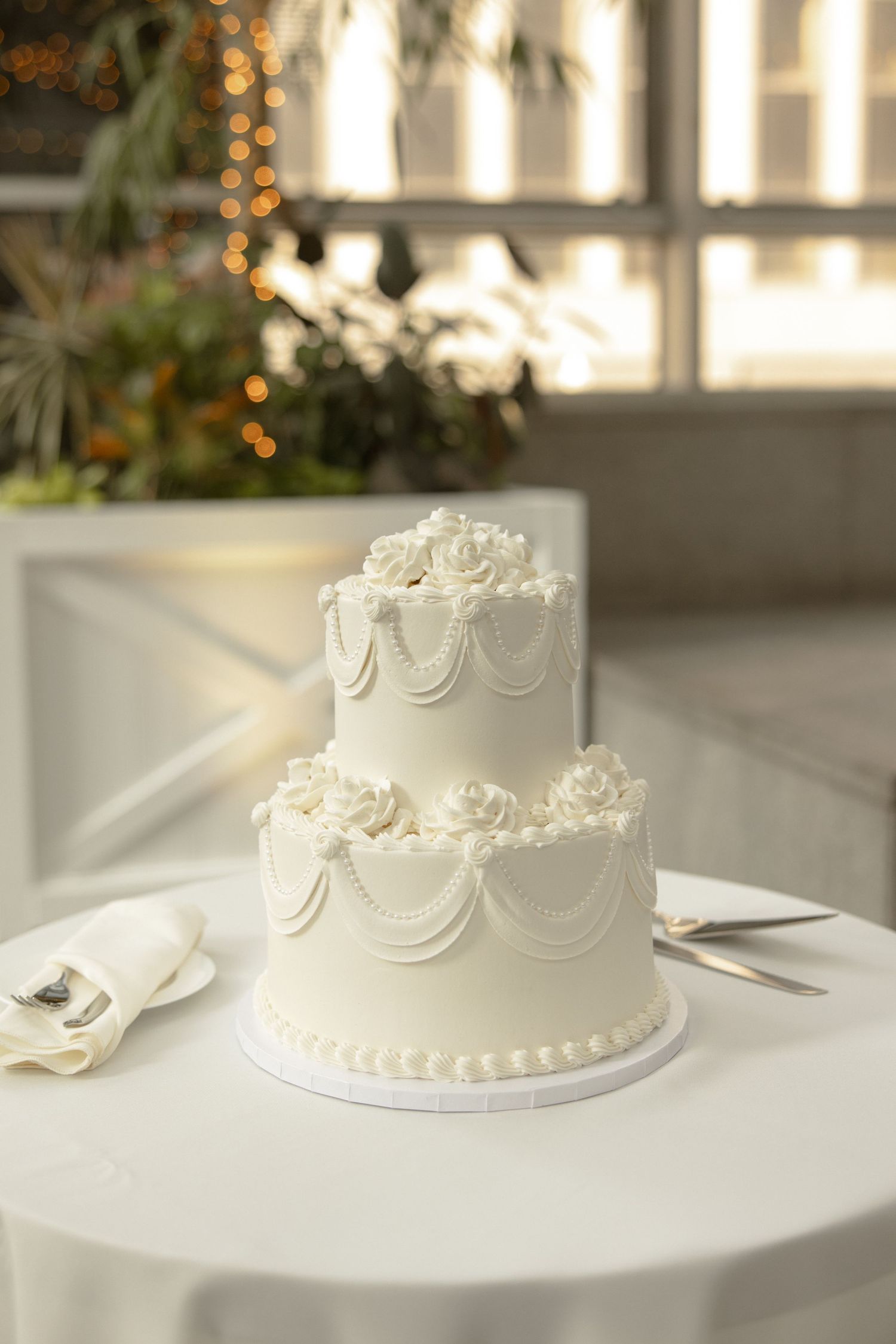 Classic two-tier white wedding cake with piped details and delicate swag decorations.