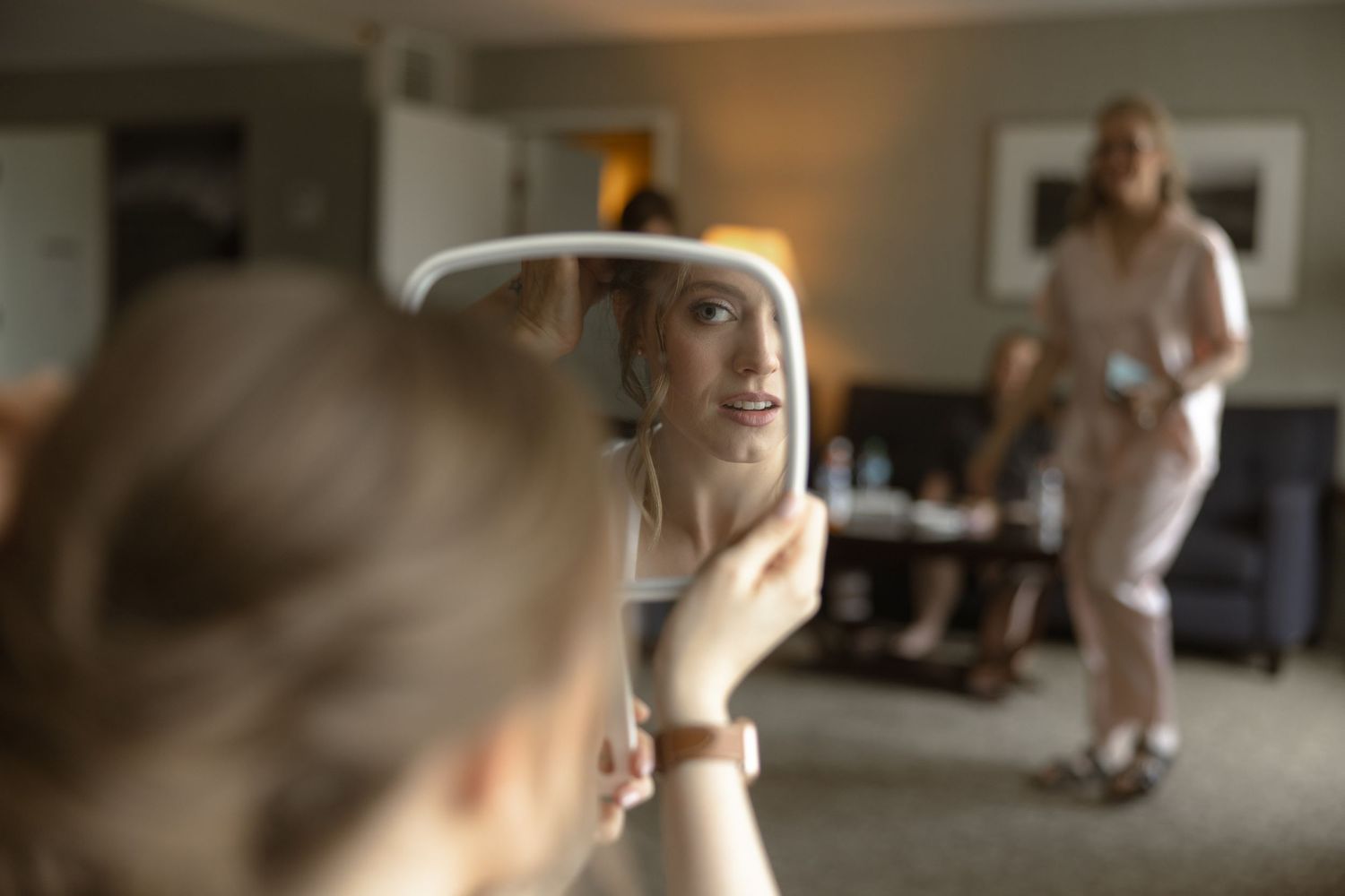 Mirror reflection shows preparation moments before wedding ceremony.