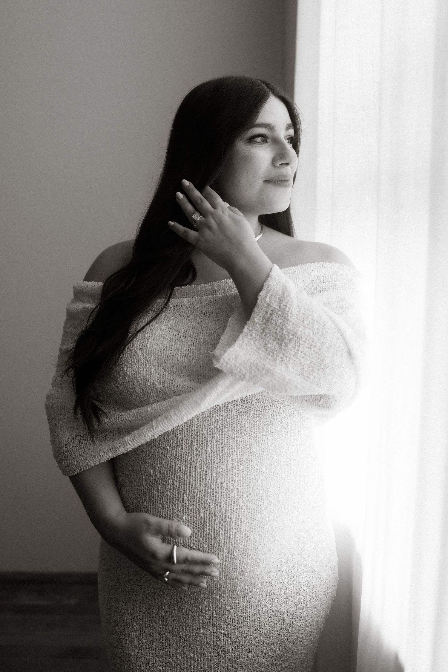 Artistic maternity photos showing a woman in white wrapped clothing against backlit window creating ethereal glow effects.