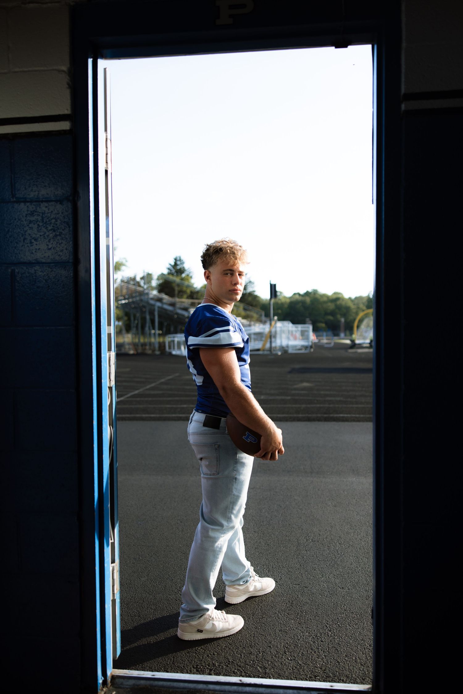 Figure in athletic wear stands framed in doorway against bright white background.