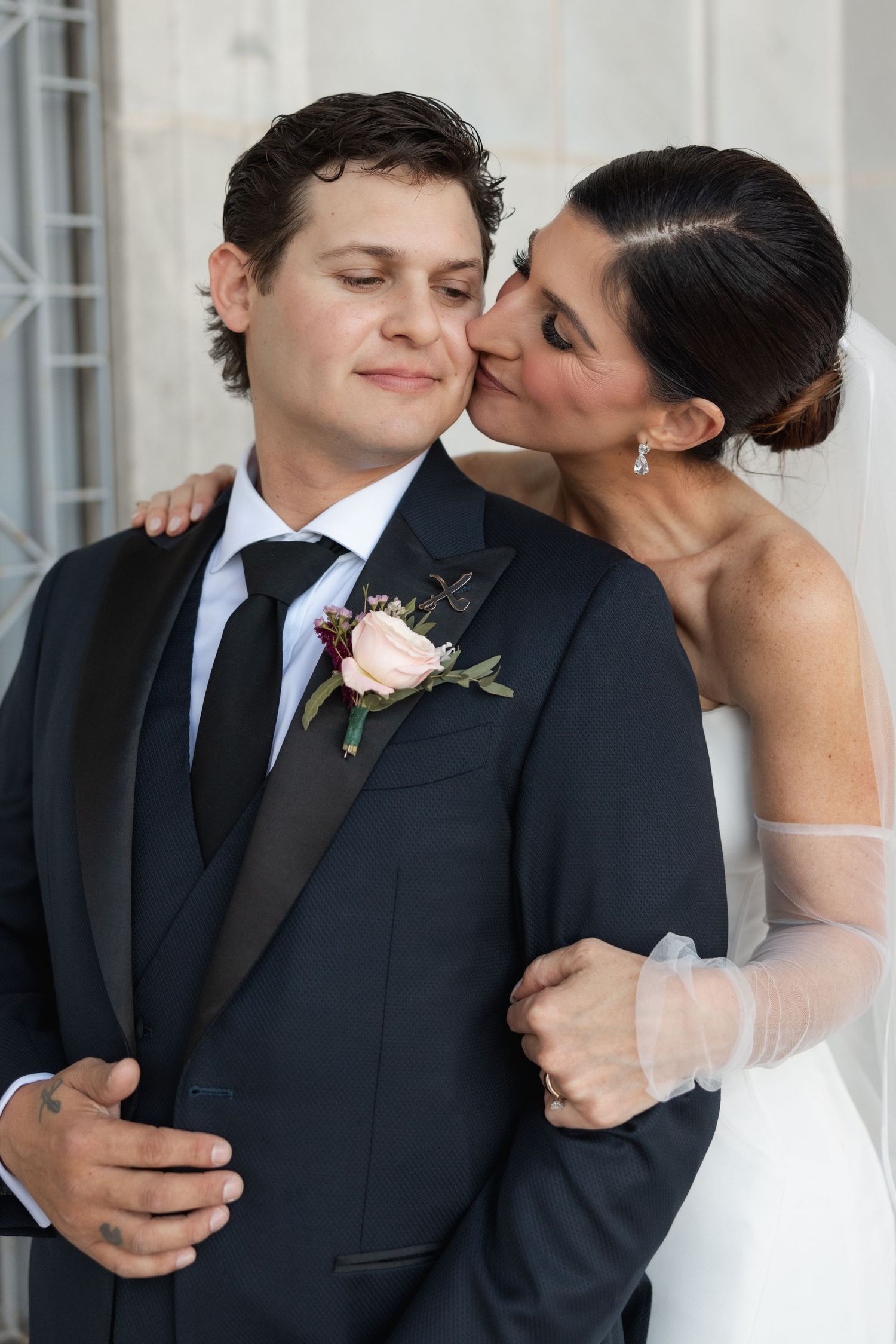 Intimate wedding photography series showing a tender moment between couple in formal attire against white columns.