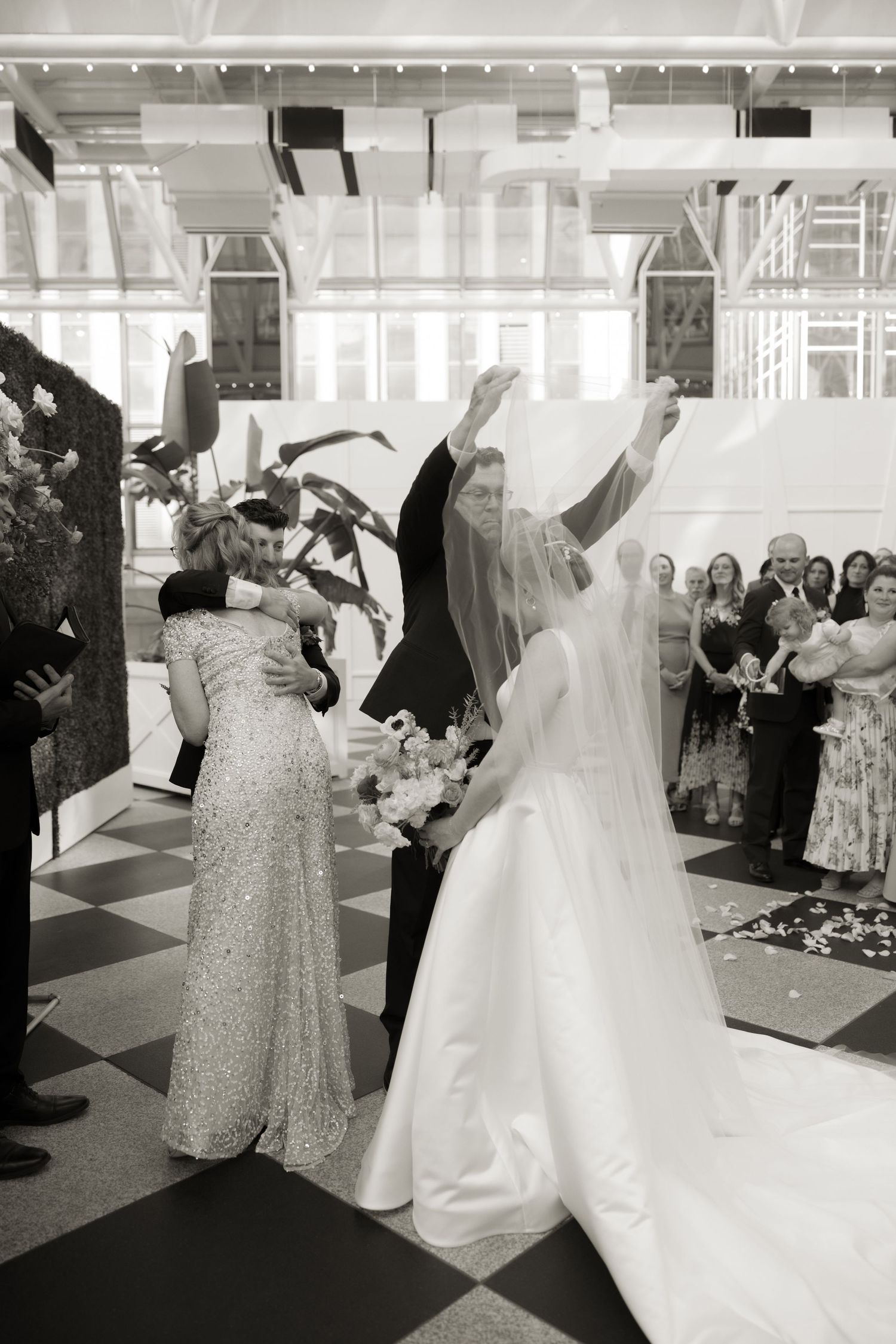 Wedding guests celebrating with dancing on a black and white checkered floor at an elegant reception venue.