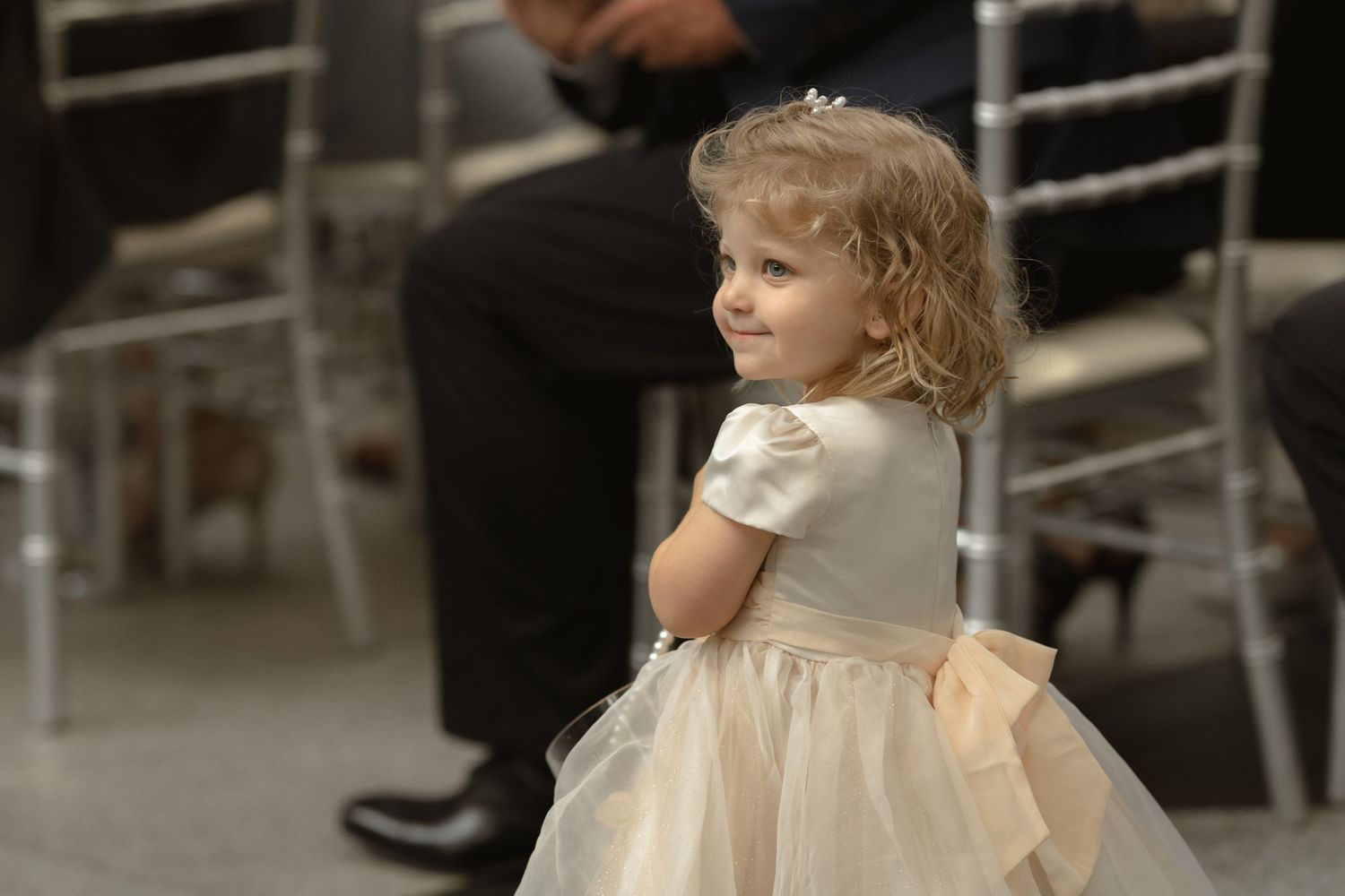 Young flower girl in cream dress with puff sleeves at wedding reception.